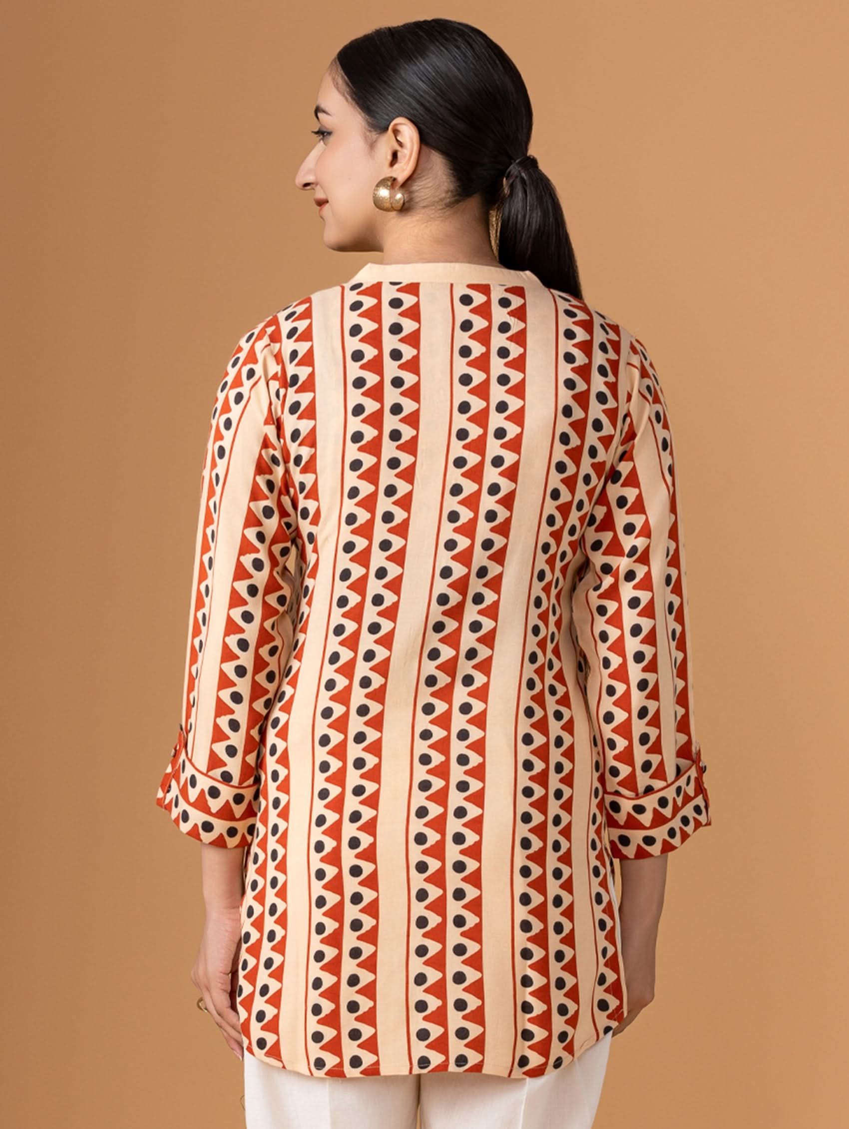 Woman wearing a patterned shirt against a brown background