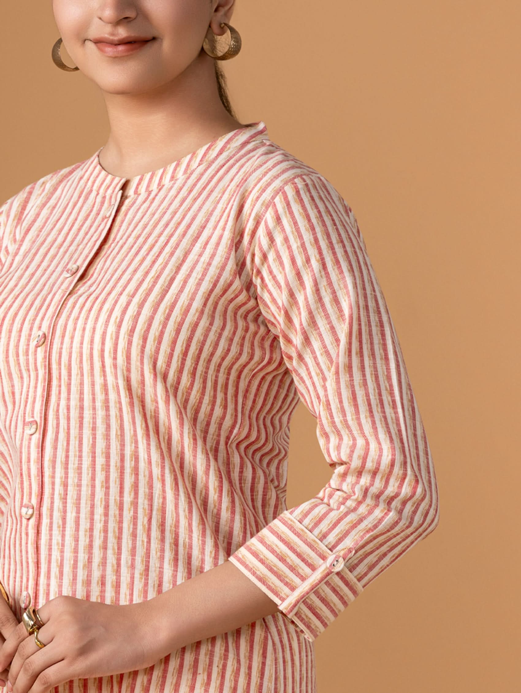 Woman wearing a pink and white striped shirt against a beige background