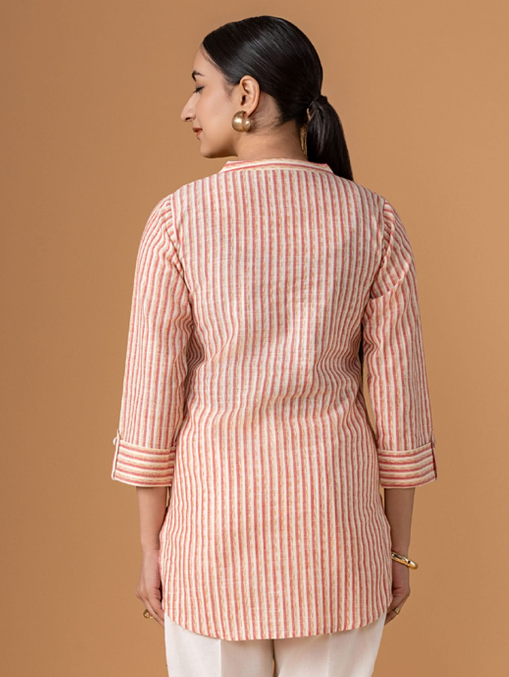 Woman wearing a pink and white striped shirt against a brown background