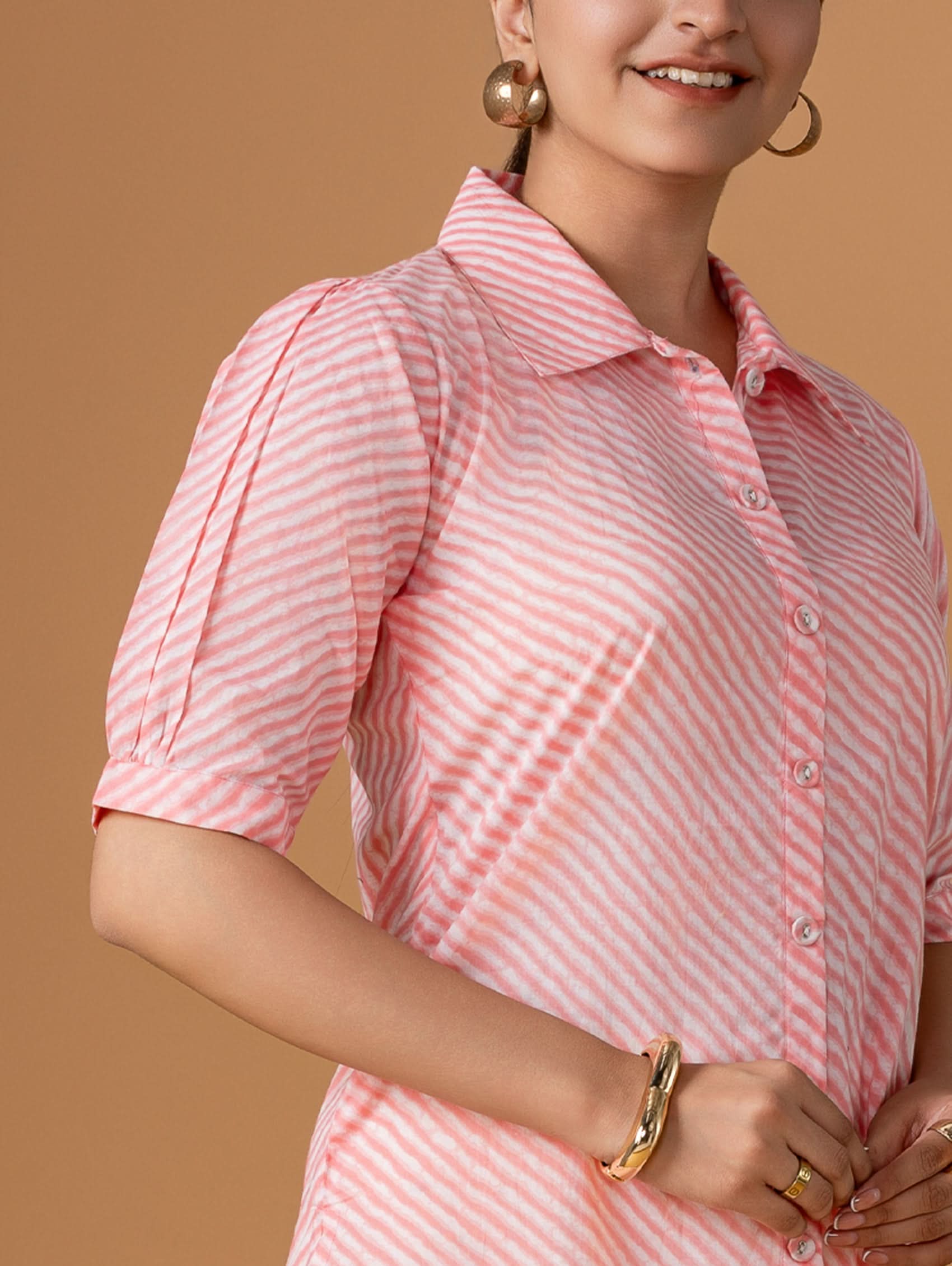 Person wearing a pink and white striped shirt against a brown background