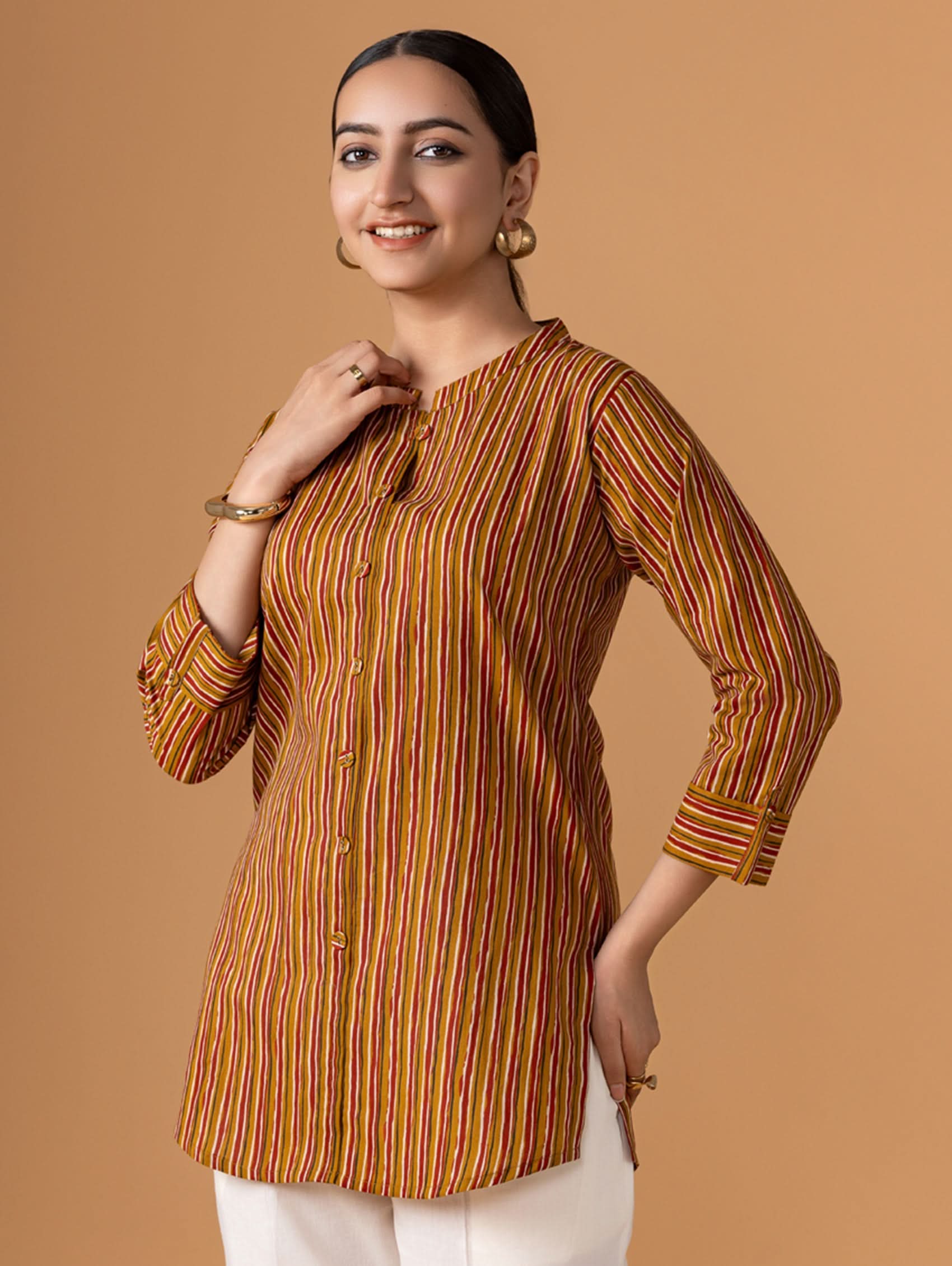 Woman wearing a striped brown and orange kurta against a brown background