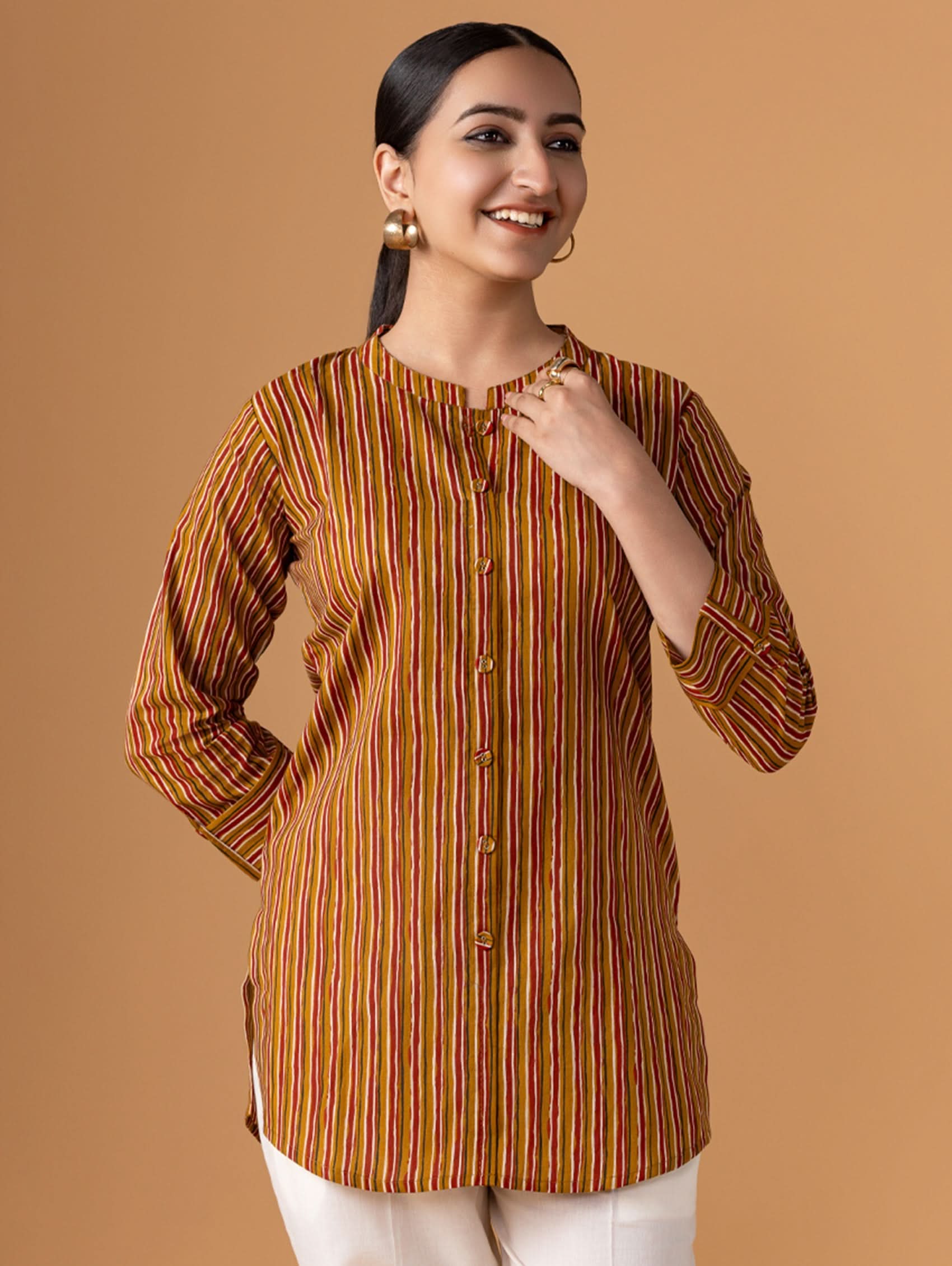 Woman wearing a brown and orange striped shirt against a beige background