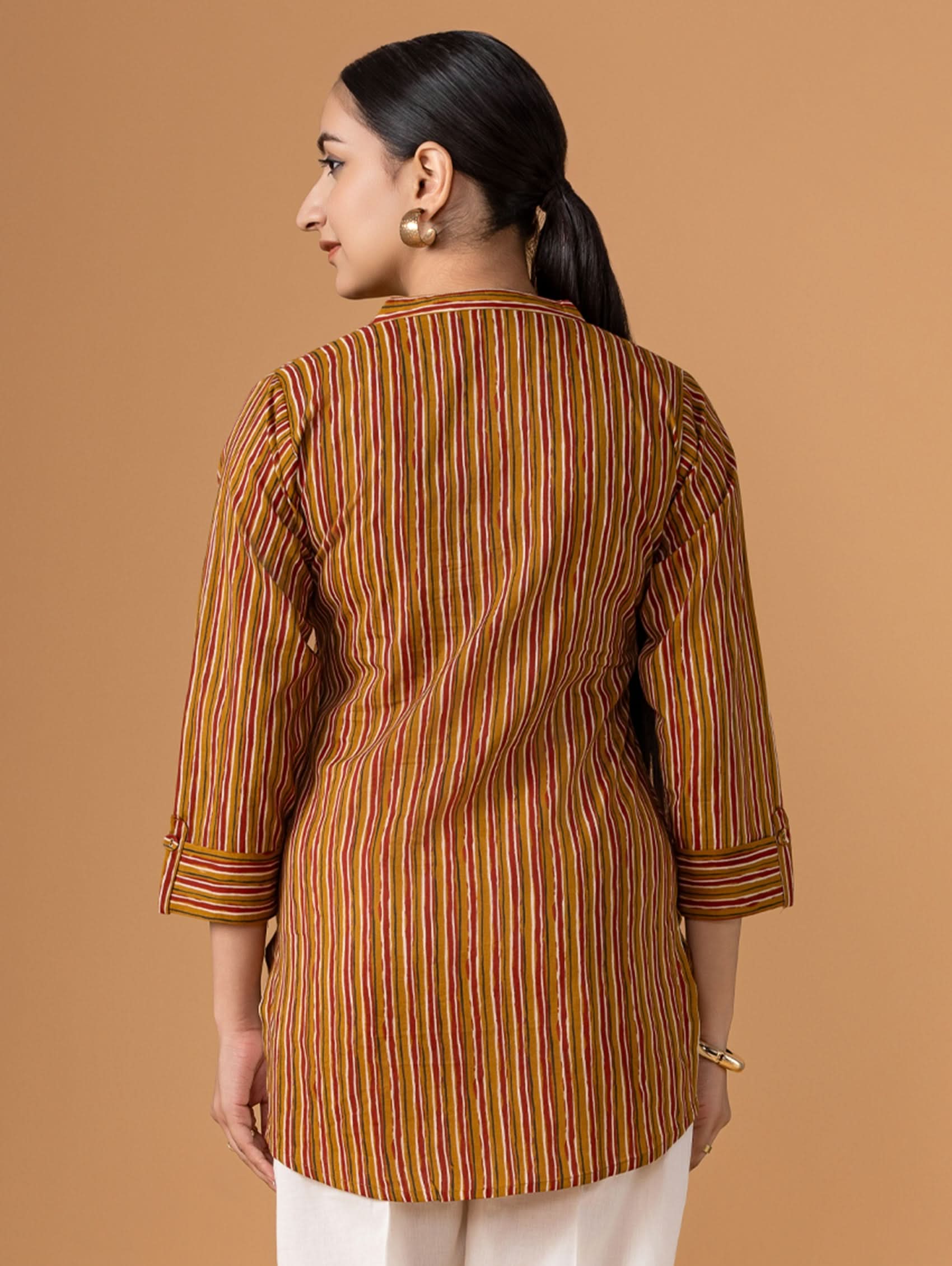 Woman wearing a brown striped shirt against a beige background