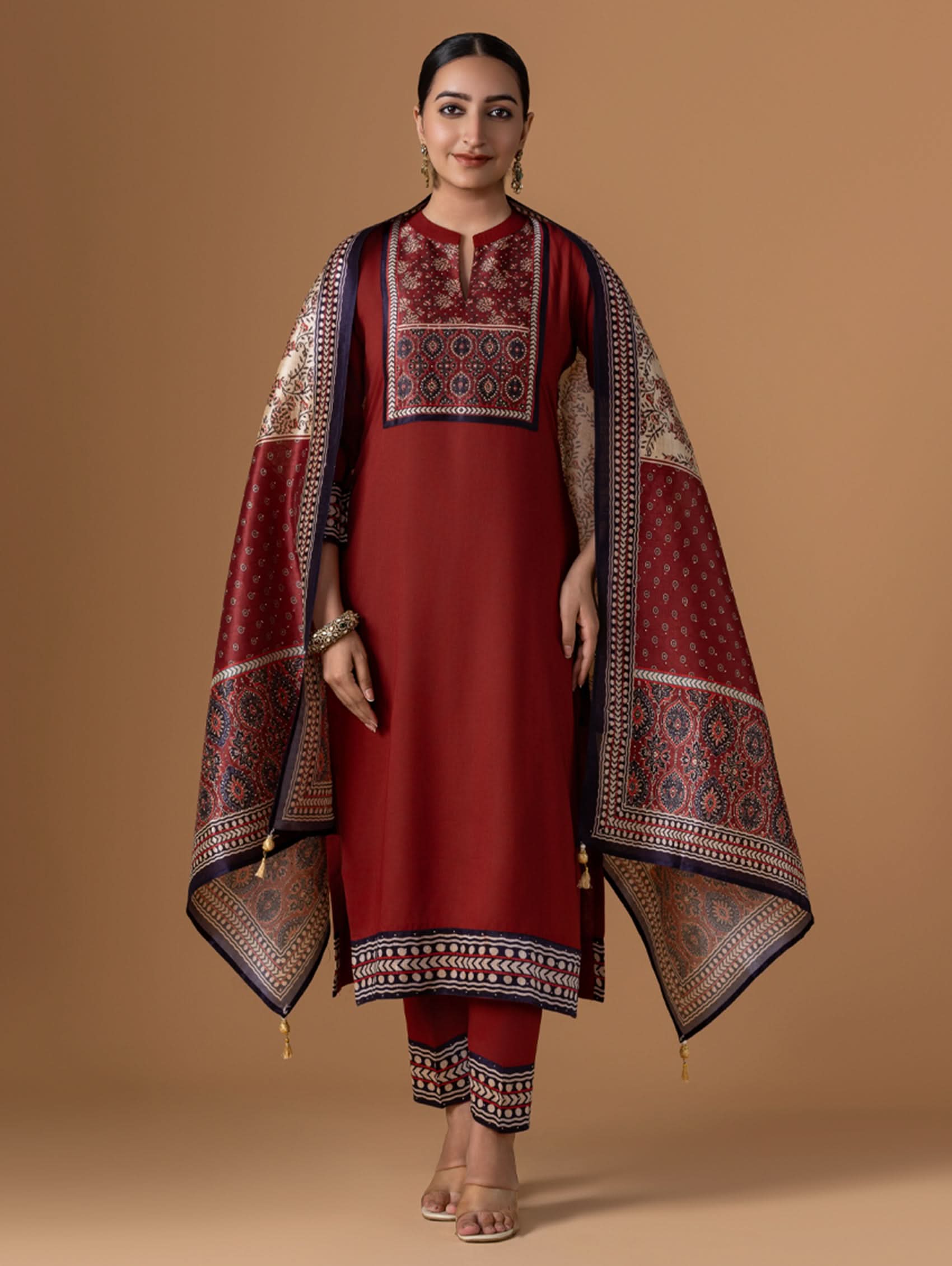 Woman wearing a red traditional outfit with a patterned shawl on a beige background
