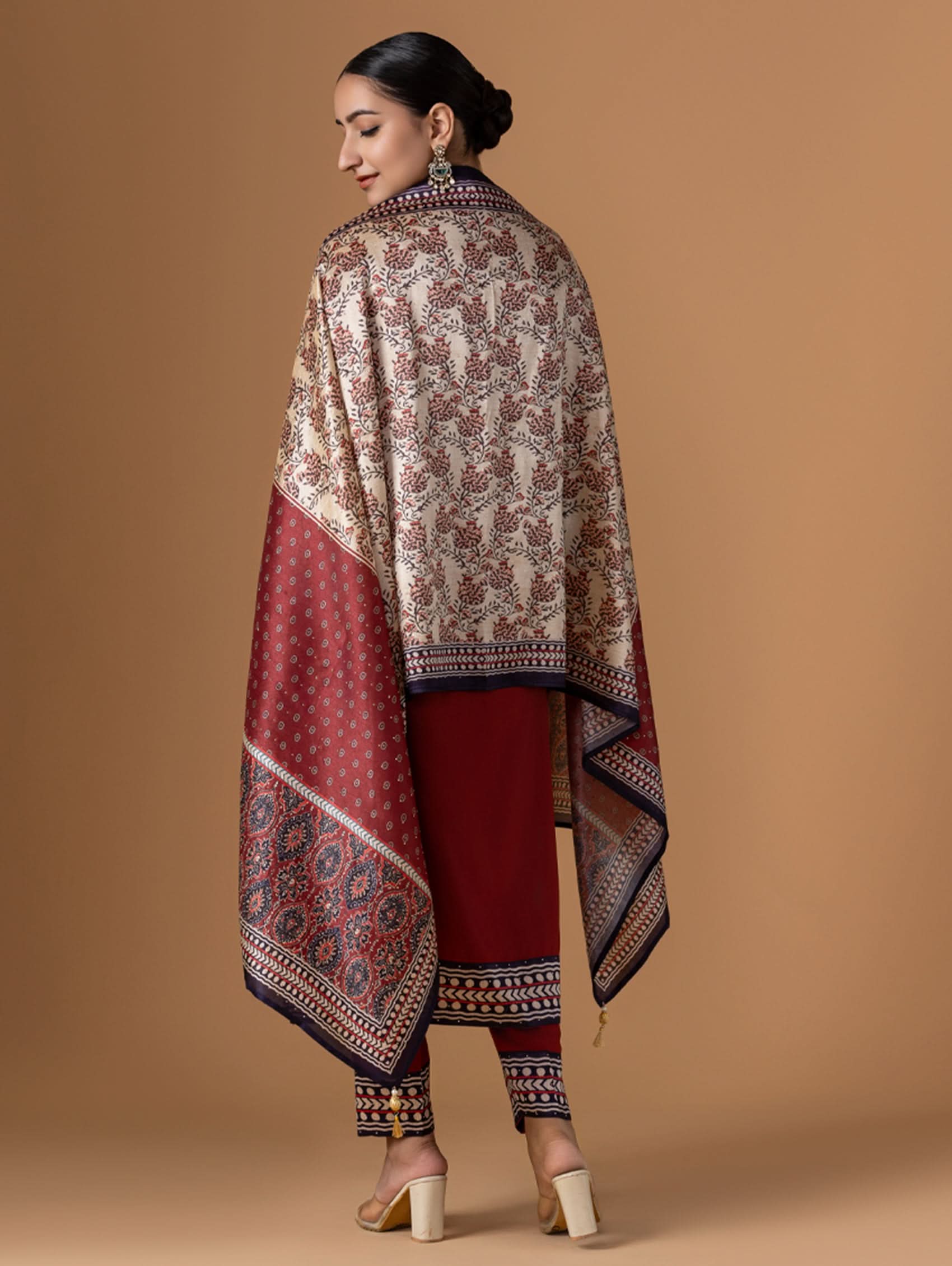 Woman wearing a patterned shawl and red outfit on a beige background