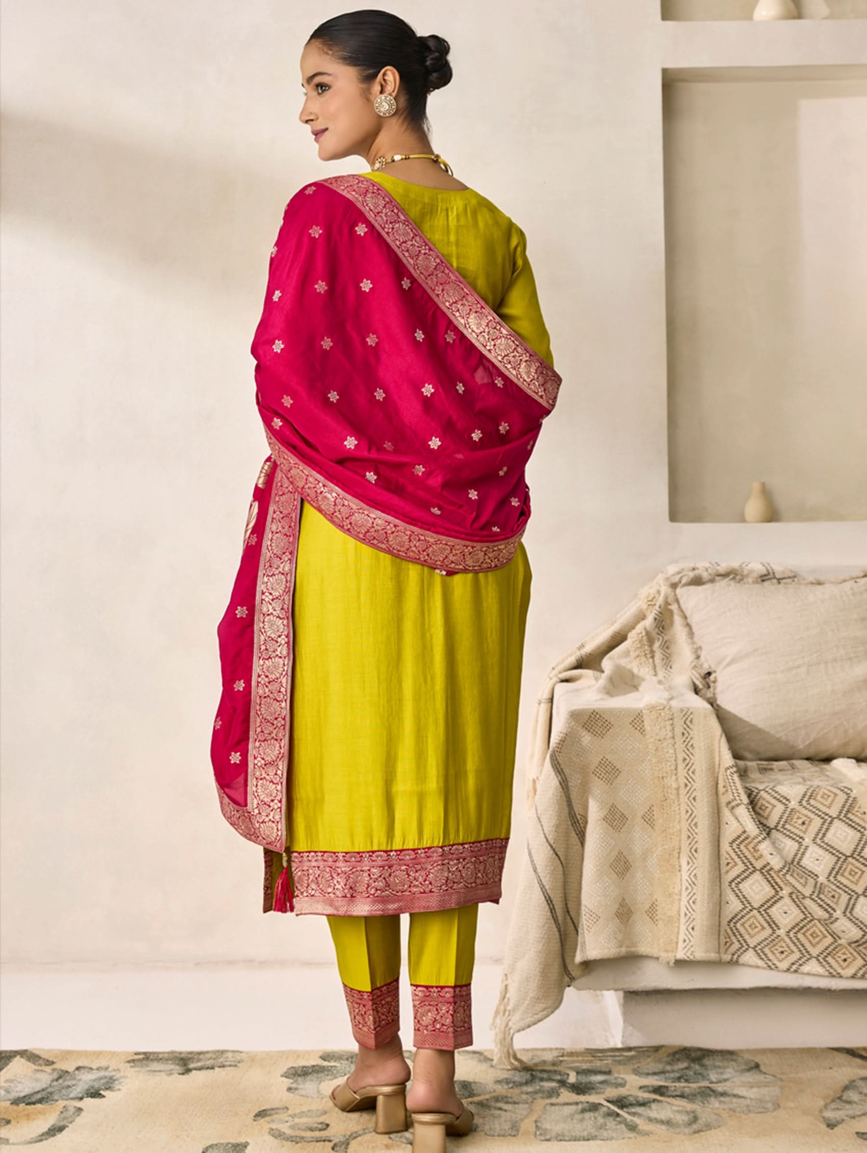 Woman wearing a yellow outfit with a pink dupatta in a room setting