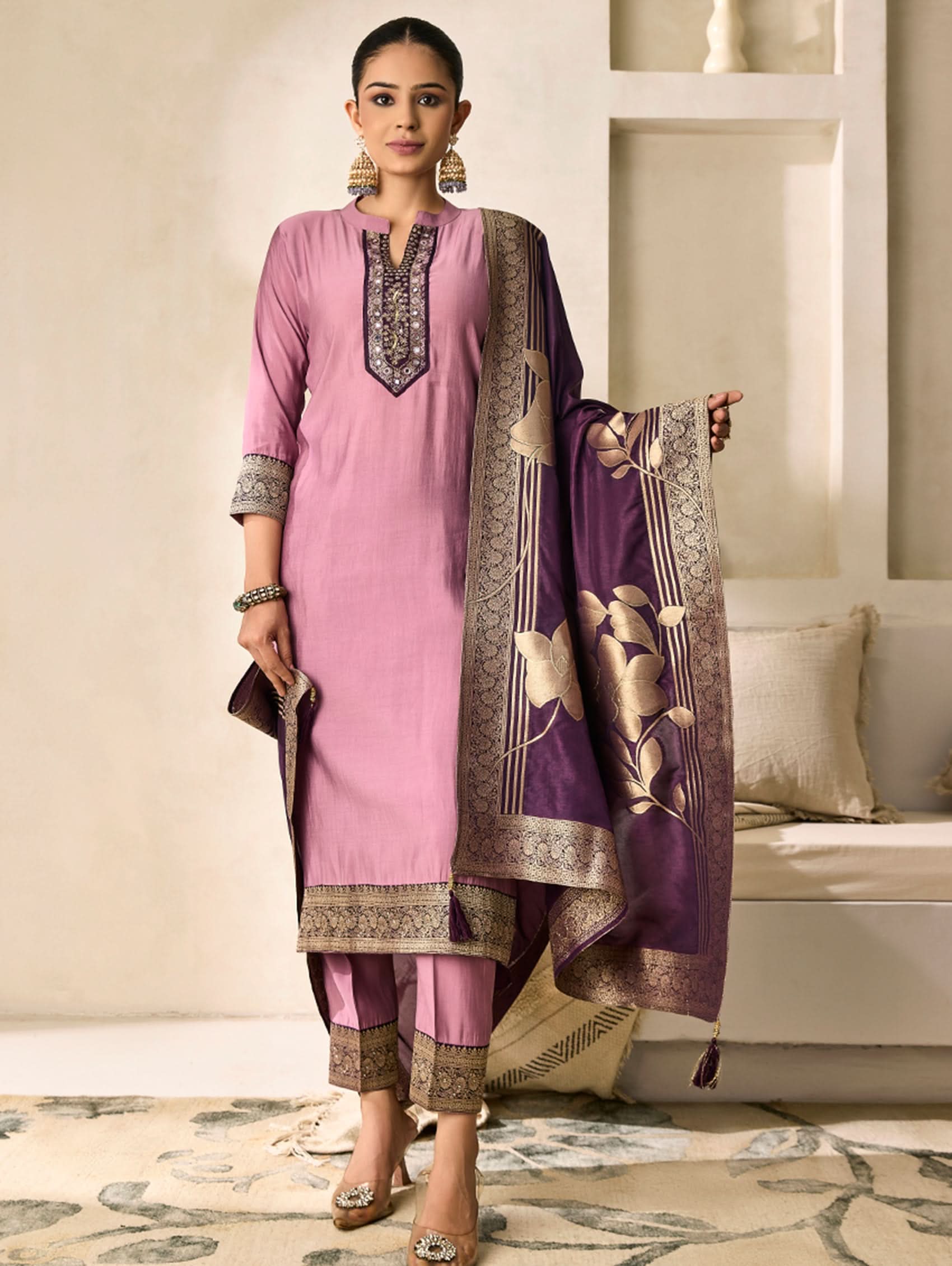 Woman wearing a pink traditional outfit with a purple dupatta in an indoor setting