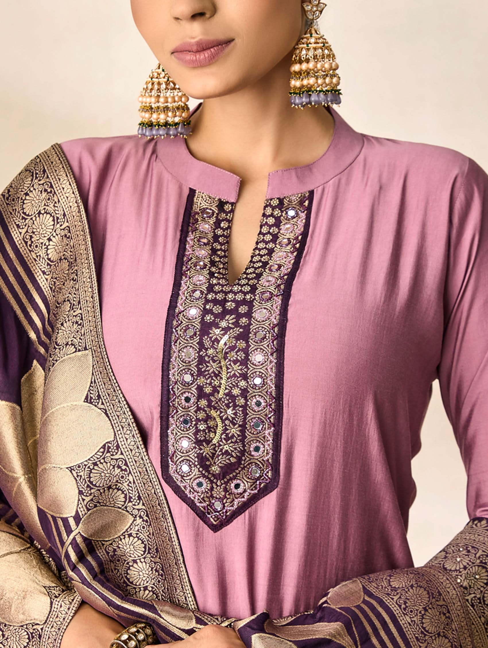 Pink embroidered top with gold and purple details, worn by a person.