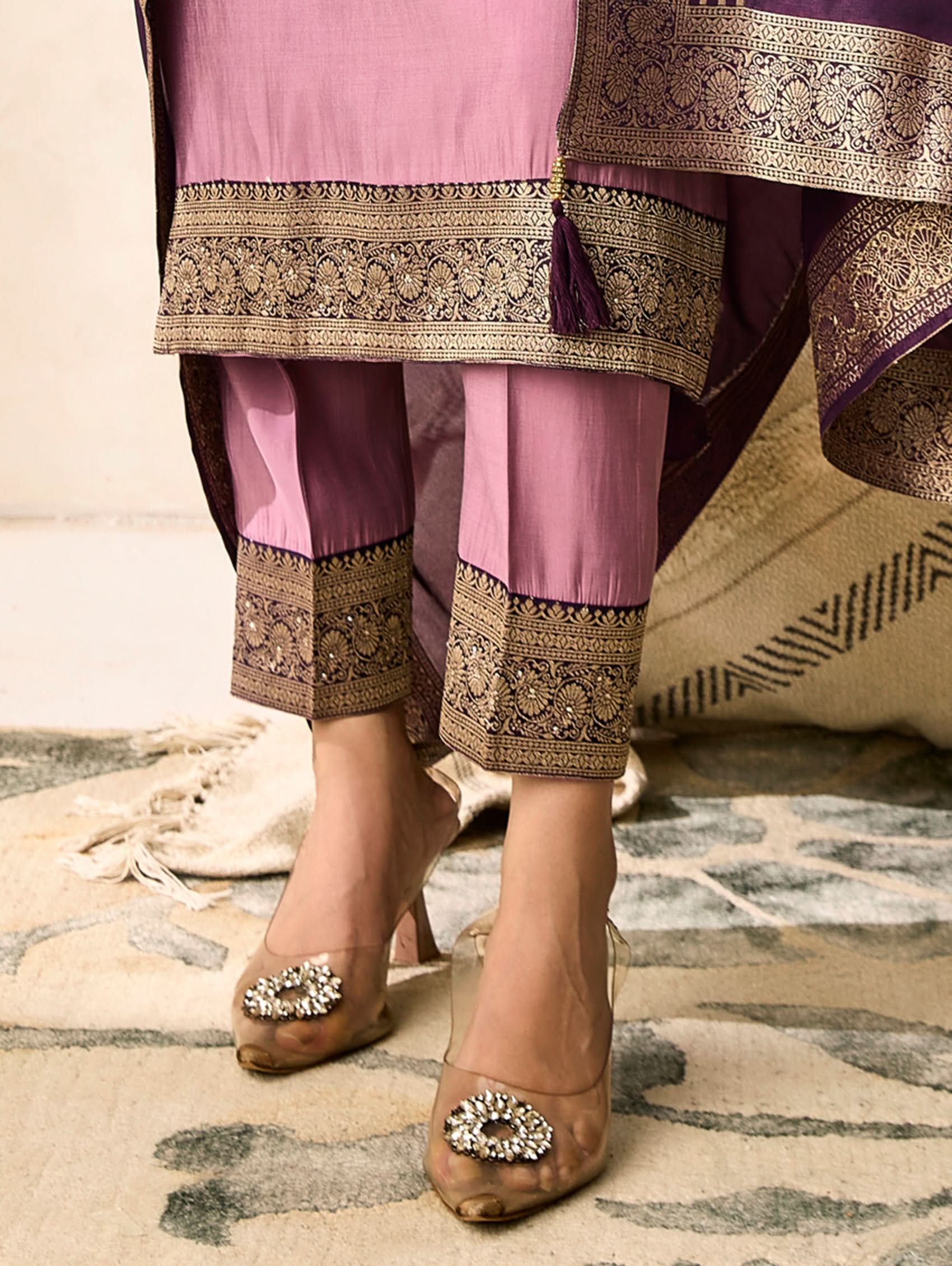 Traditional outfit with pink top and purple pants on a patterned rug