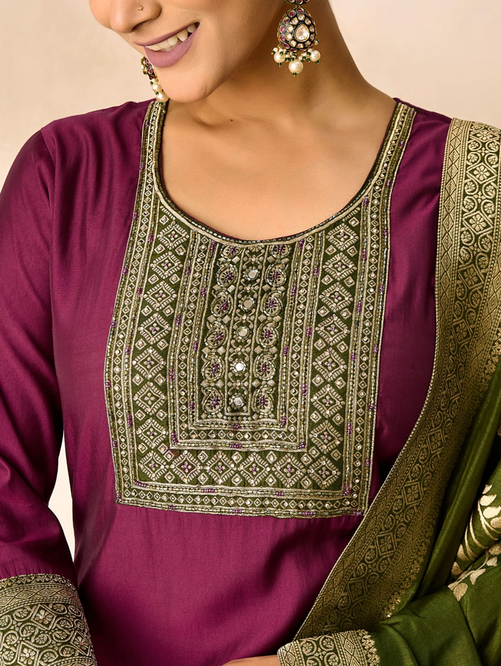 Purple traditional outfit with intricate gold embroidery on a beige background