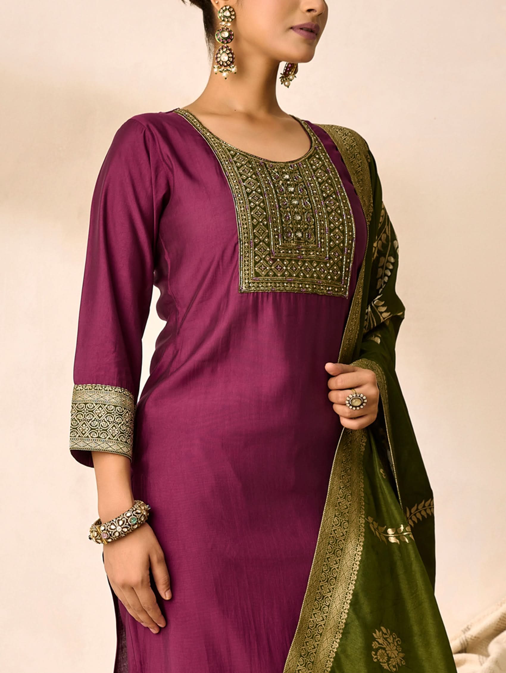 Woman wearing a purple and green traditional outfit with embroidery details.