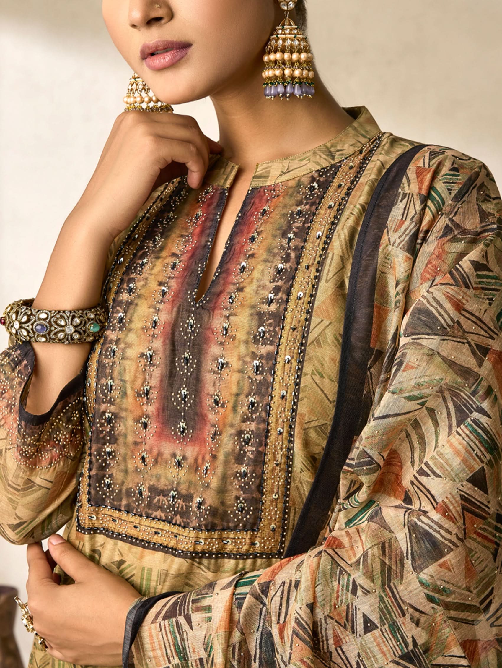 Woman wearing a patterned outfit with intricate details and jewelry.