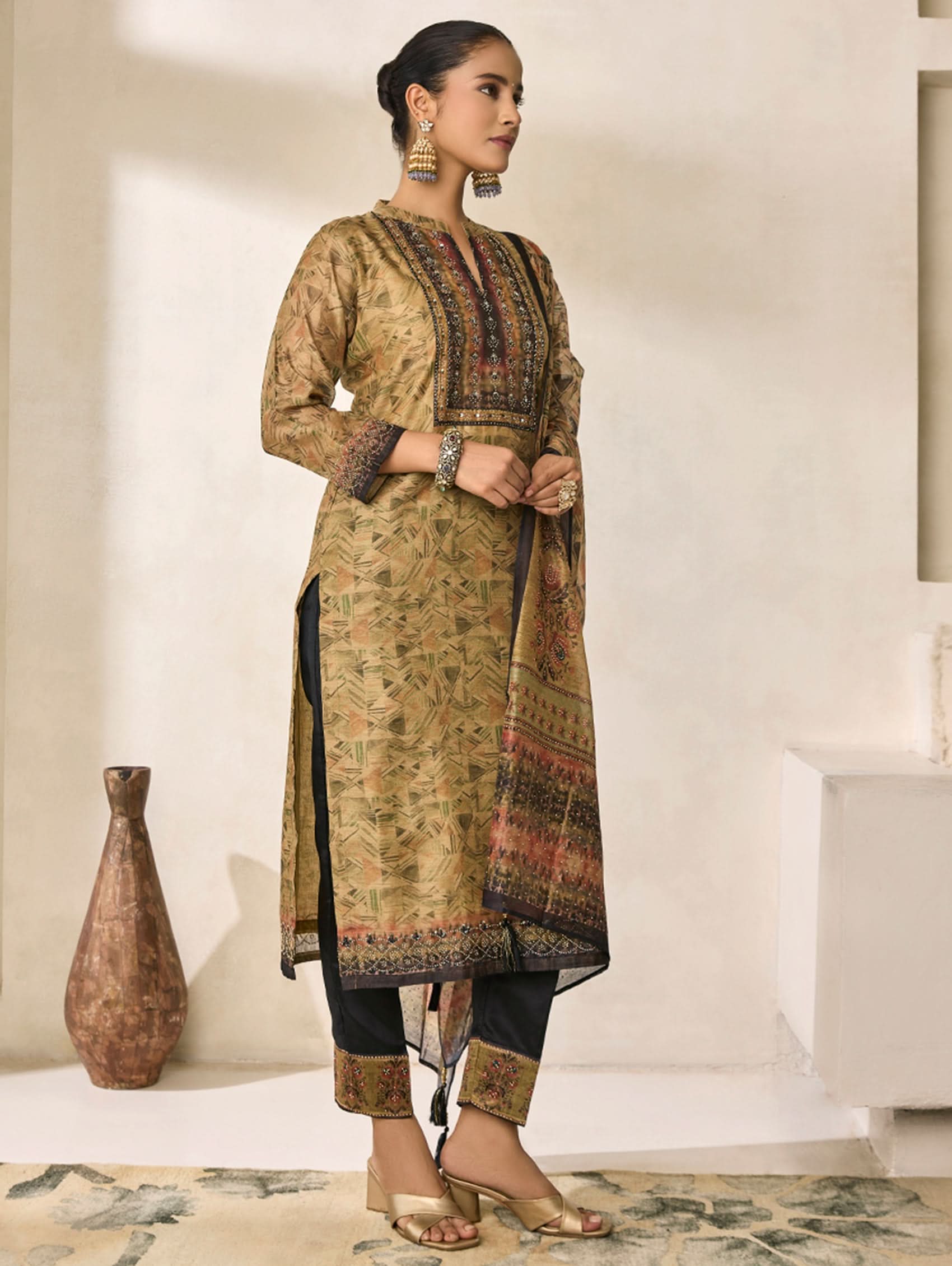 Woman wearing a traditional outfit with intricate patterns in a minimalistic setting.