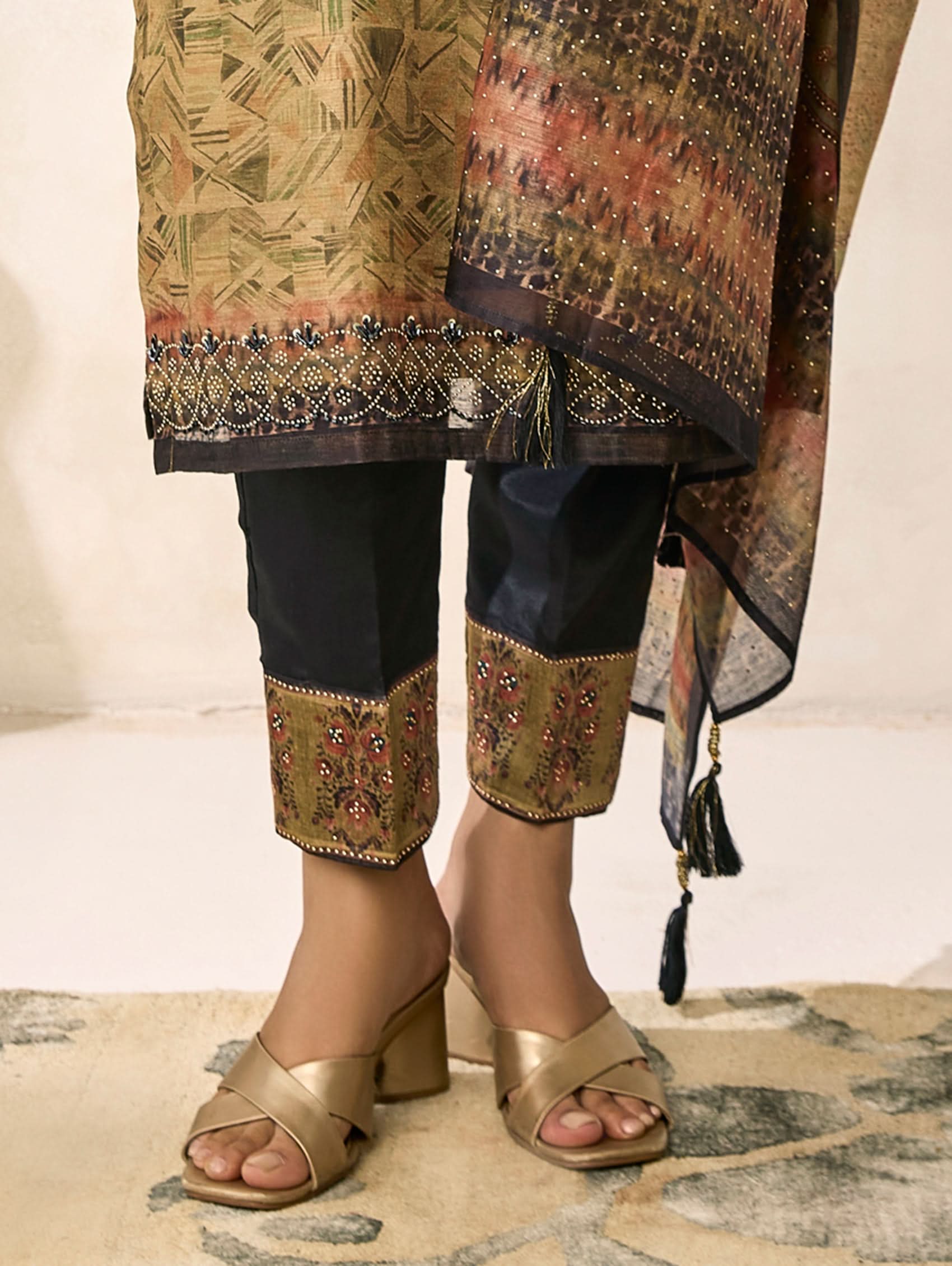 Traditional outfit with embroidered top and pants, gold sandals, and a patterned shawl.