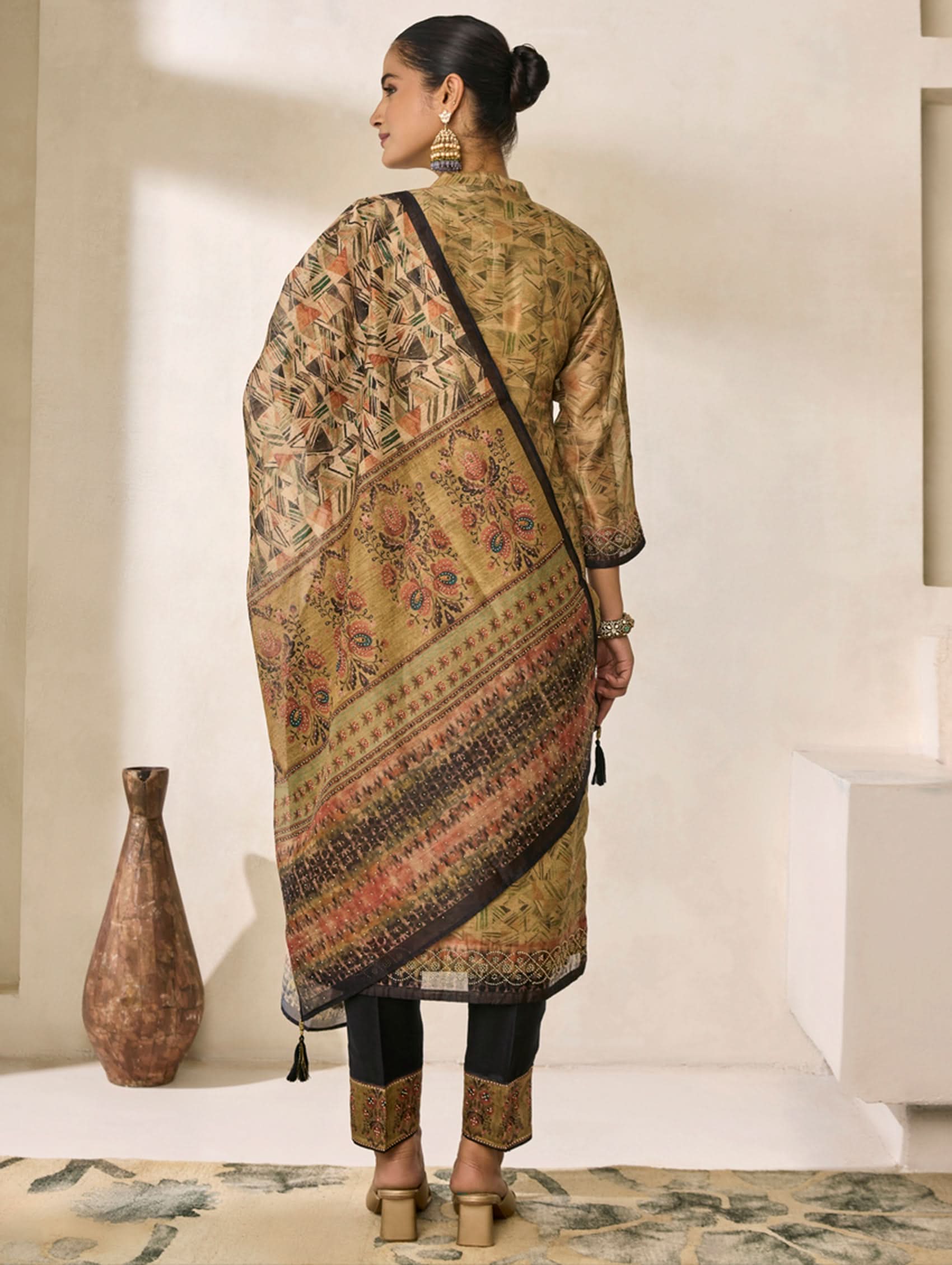 Woman wearing a traditional outfit with a patterned shawl in a minimalistic setting