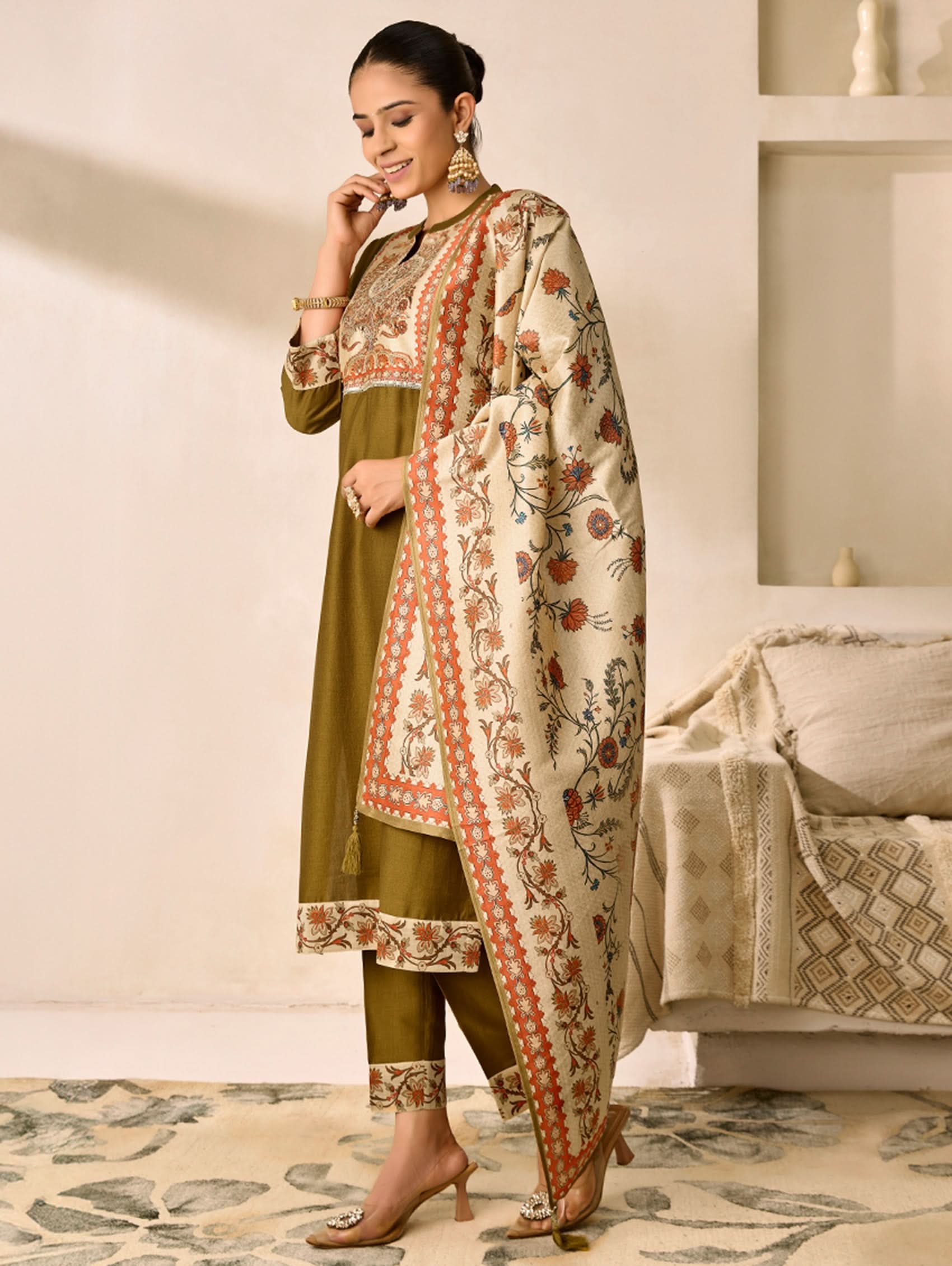 Woman wearing a traditional outfit with a floral dupatta in a home setting