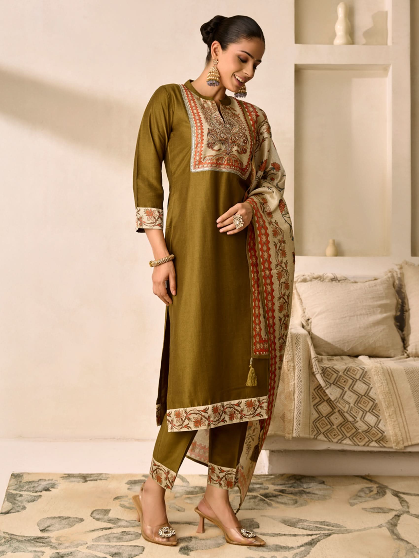 Woman wearing a traditional outfit with embroidery in a living room setting