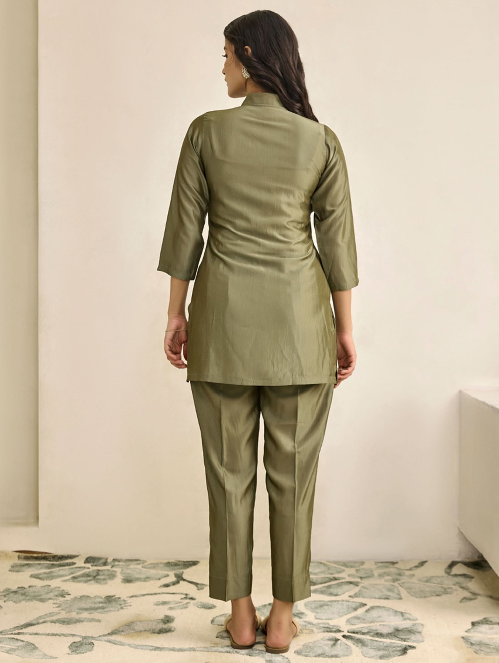 Woman wearing a green outfit standing against a plain background