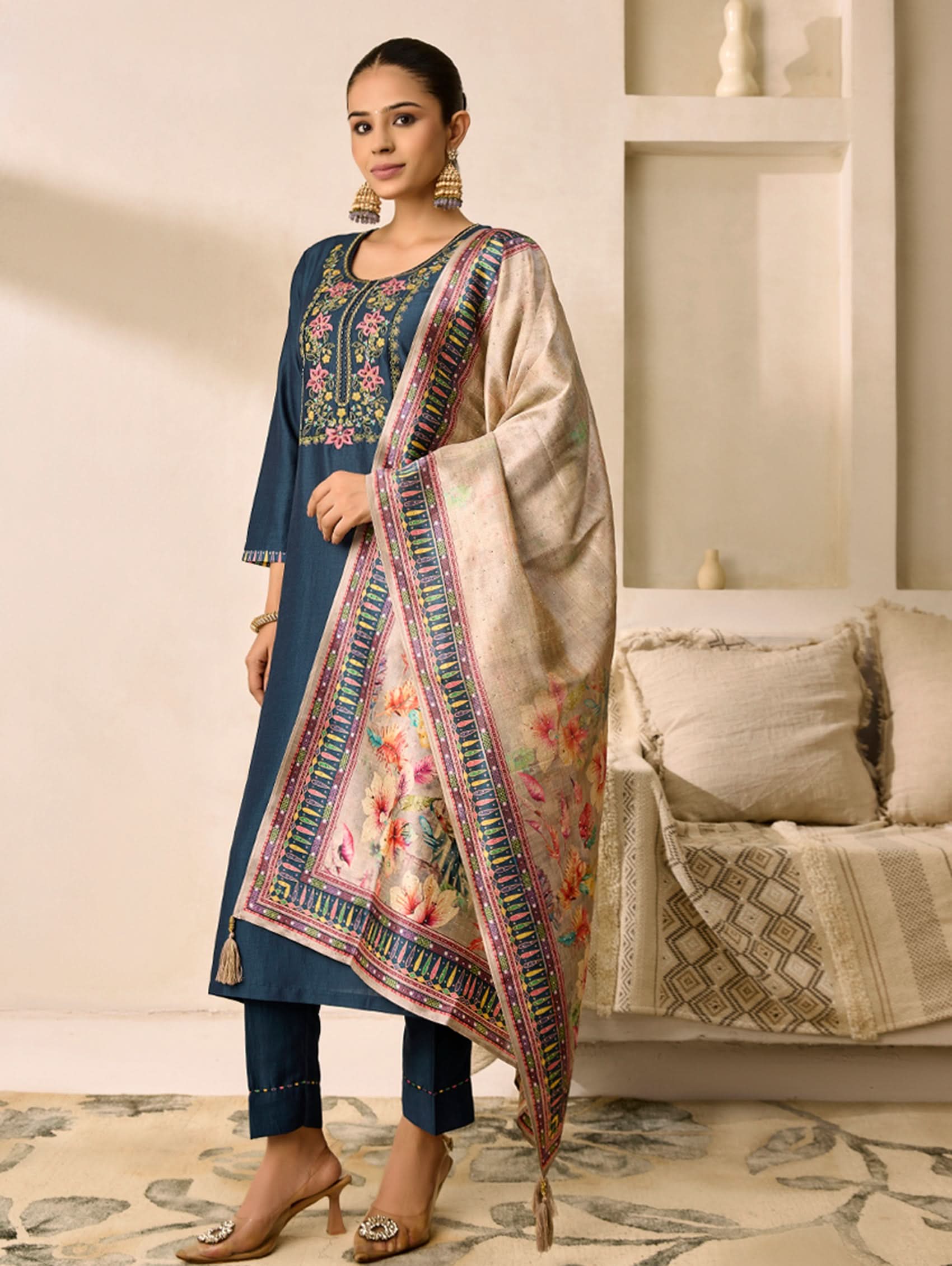 Woman wearing a traditional outfit with a floral dupatta in a living room setting