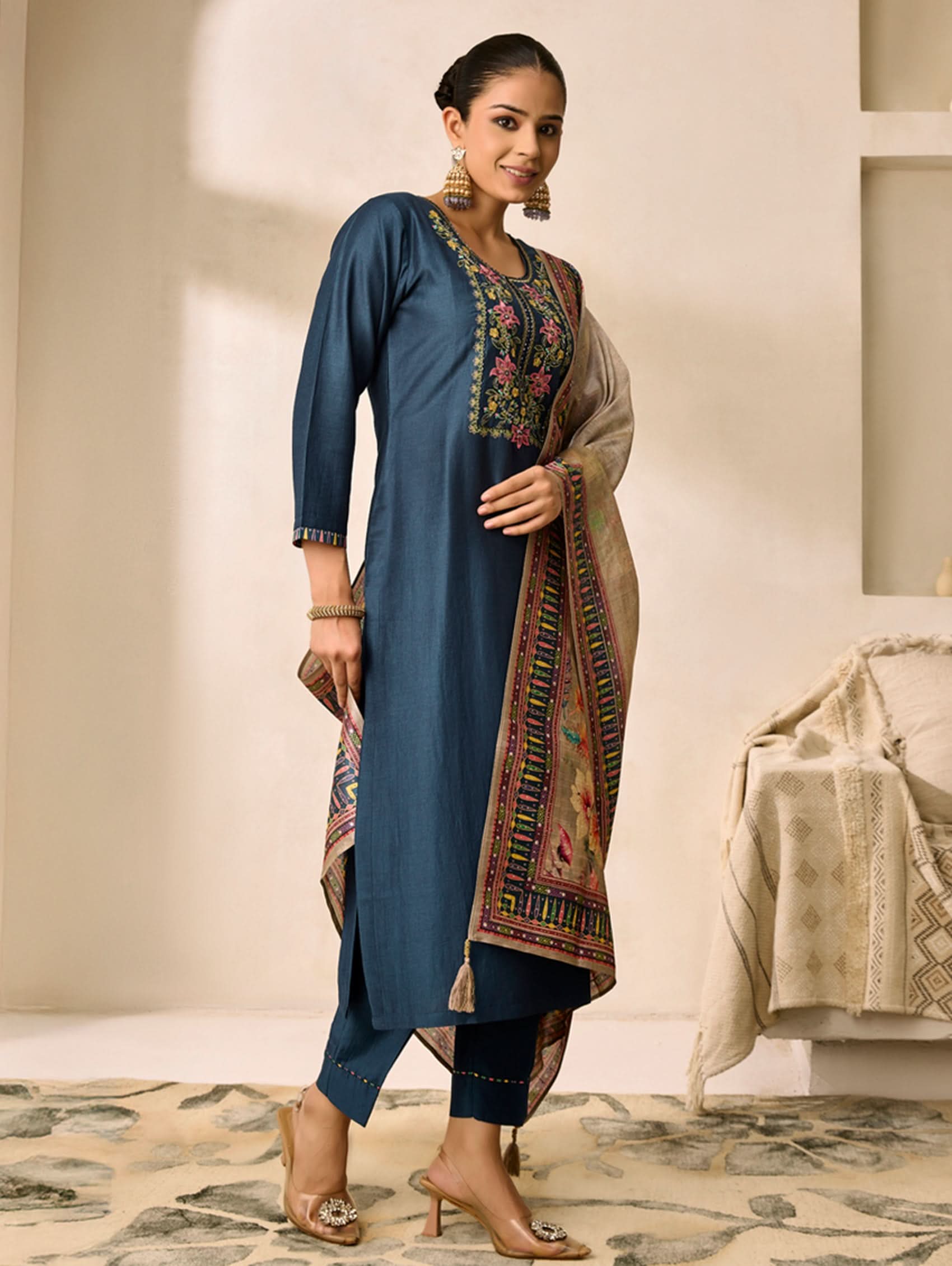 Woman wearing a blue embroidered kurta with a patterned dupatta in a room.