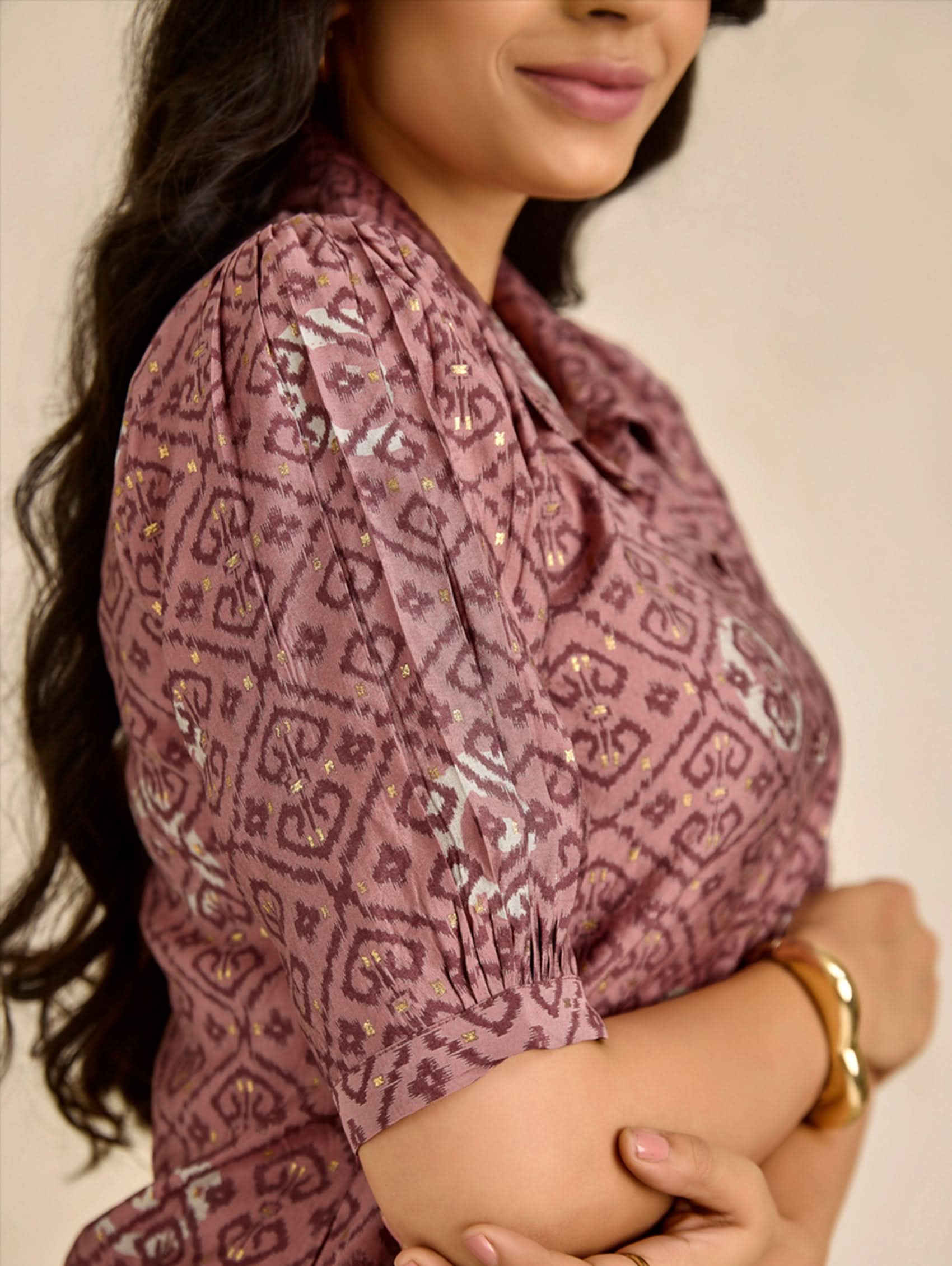 Woman wearing a patterned blouse with sequins on a plain background