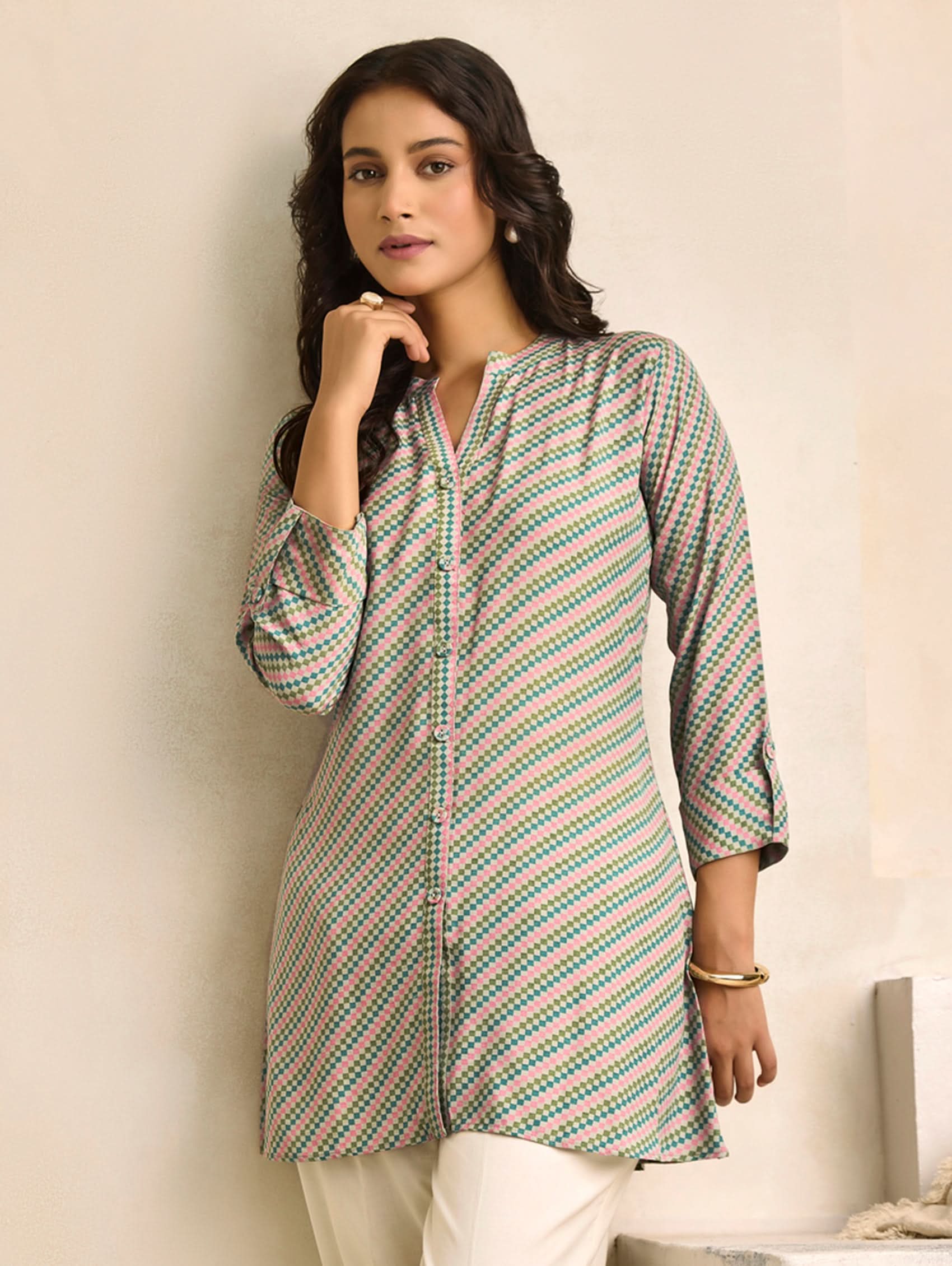 Woman wearing a patterned kurta against a plain background