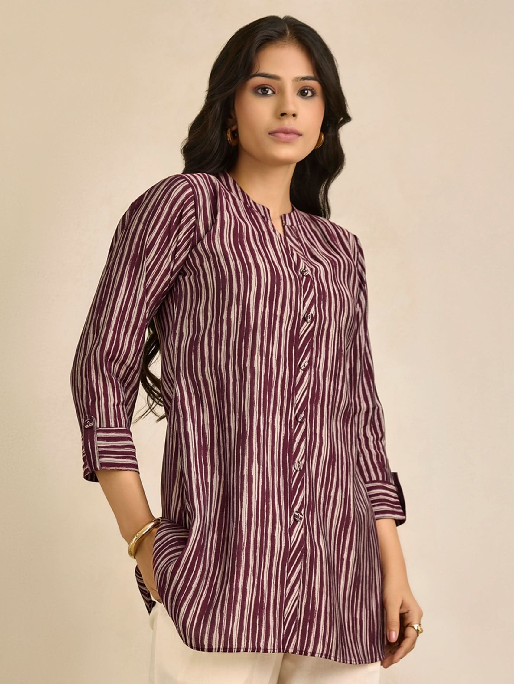 Woman wearing a maroon and white striped shirt against a beige background