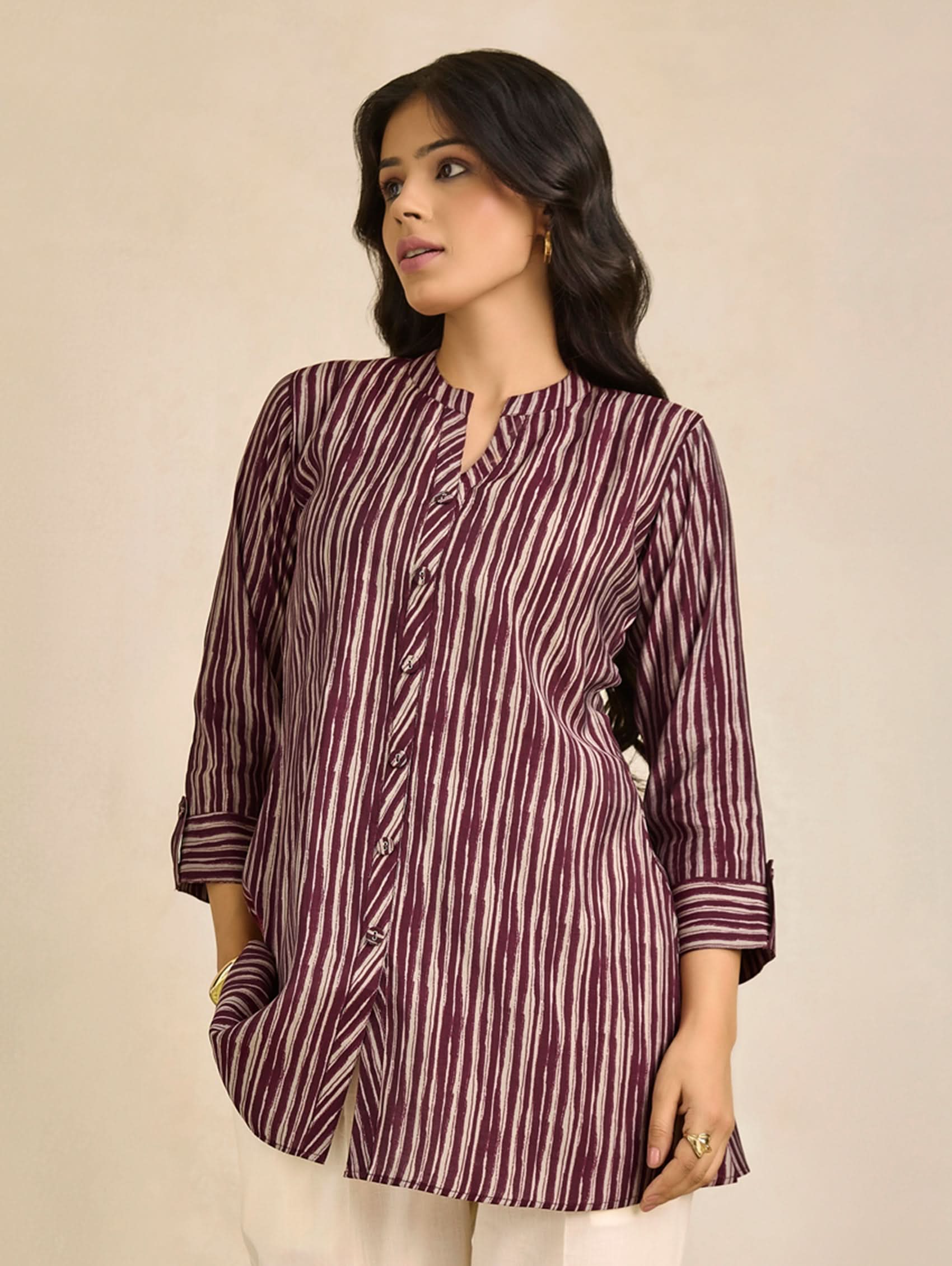 Woman wearing a maroon and white striped shirt against a beige background