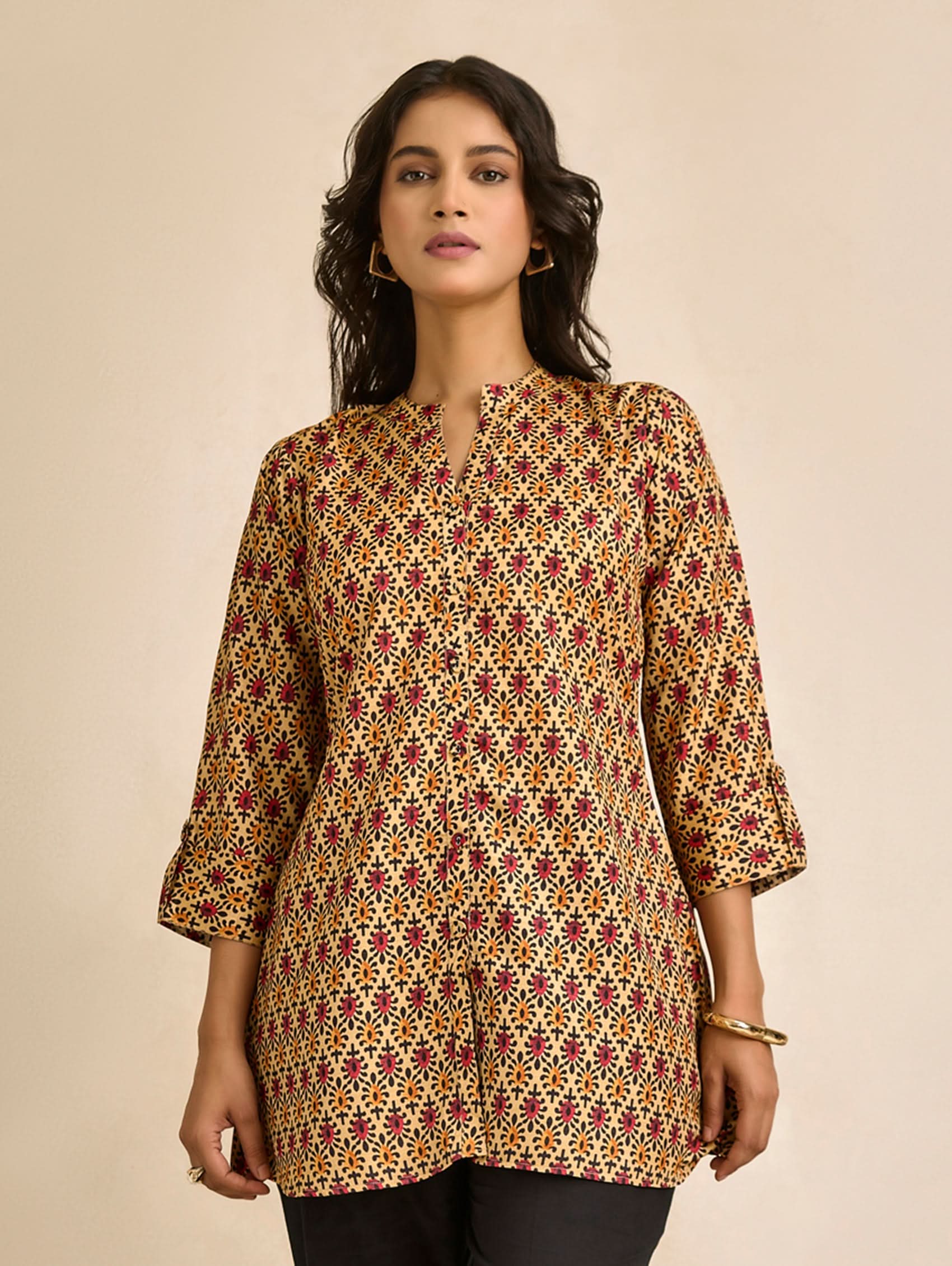Woman wearing a patterned top against a beige background