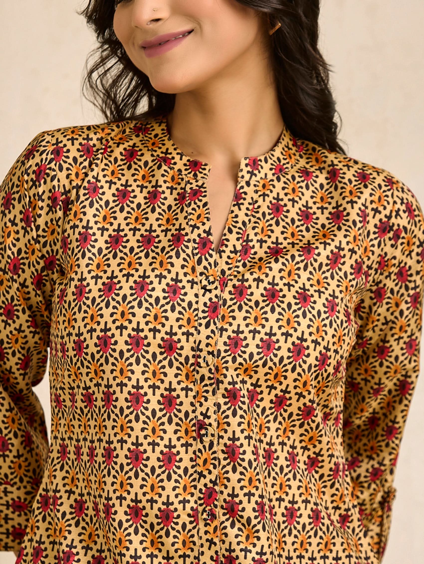 Woman wearing a patterned kurta against a beige background