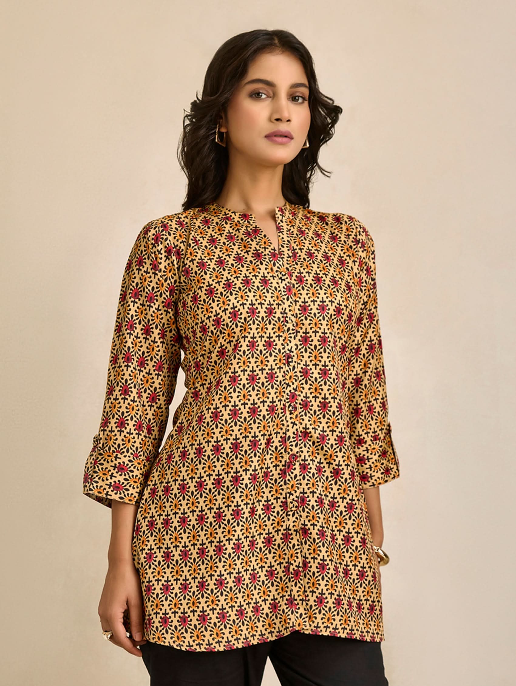Woman wearing a patterned long-sleeve top against a beige background