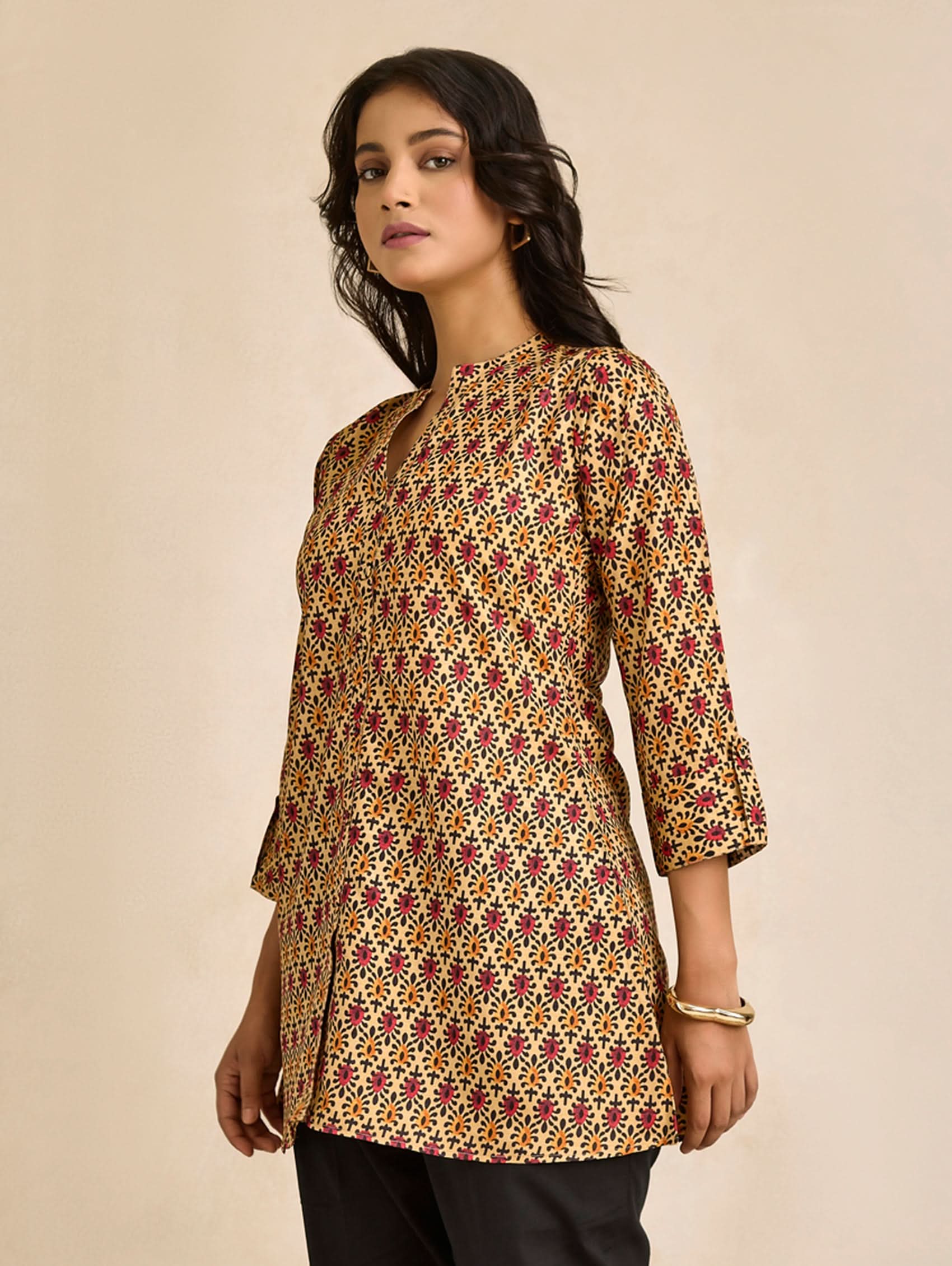 Woman wearing a patterned kurta against a beige background