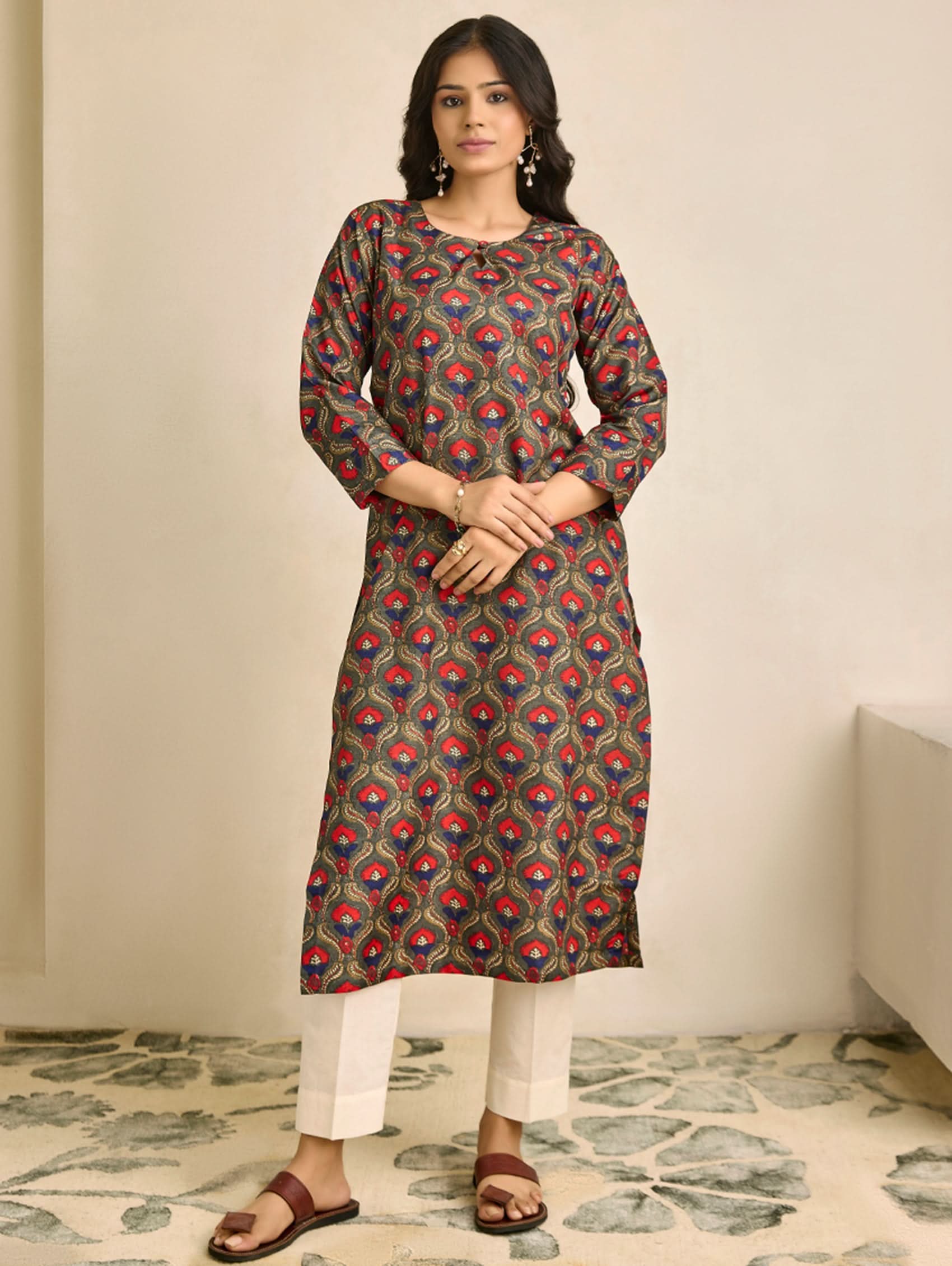 Woman wearing a patterned kurta with white pants in a room.