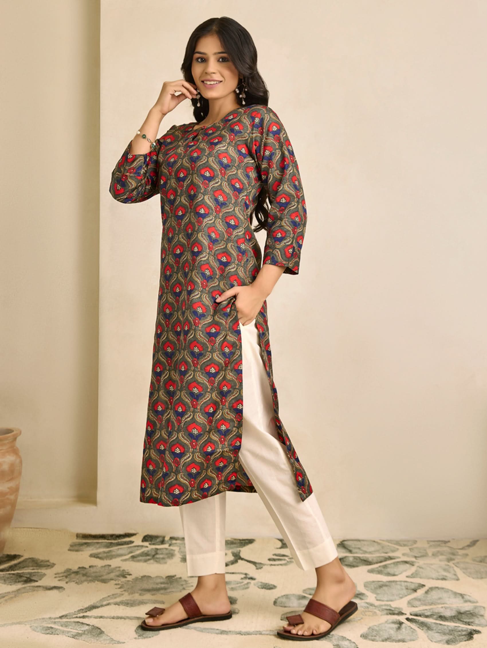 Woman wearing a patterned kurta with white pants against a neutral background
