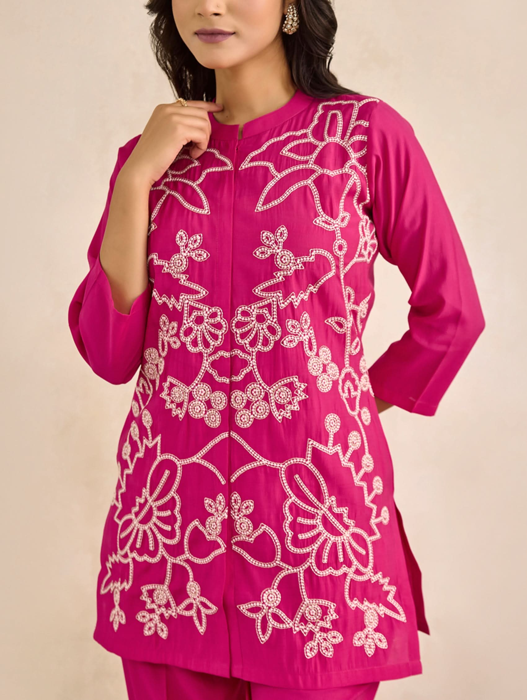 Pink embroidered outfit on a beige background
