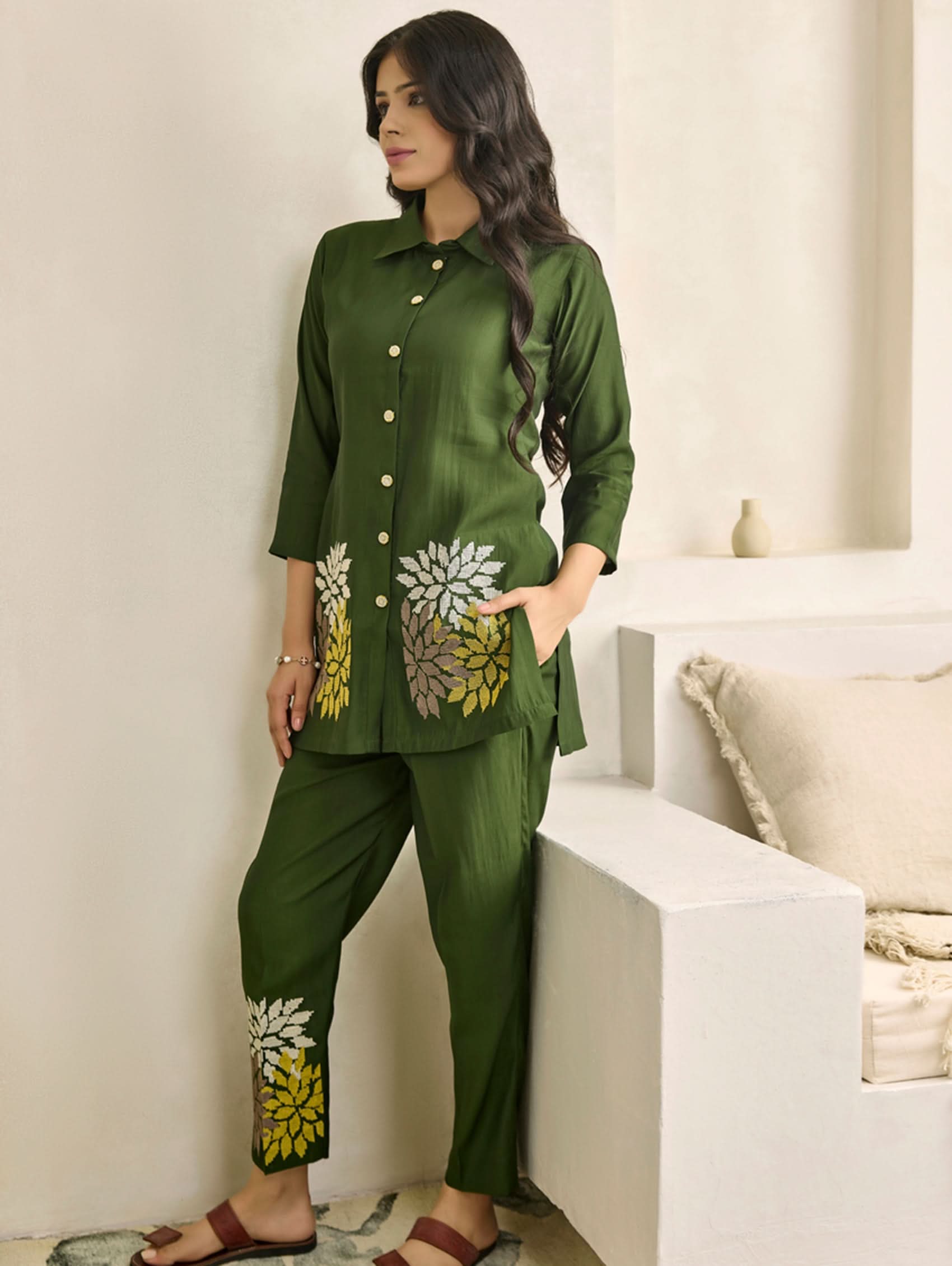 Woman wearing a green outfit with floral patterns in a minimalistic setting
