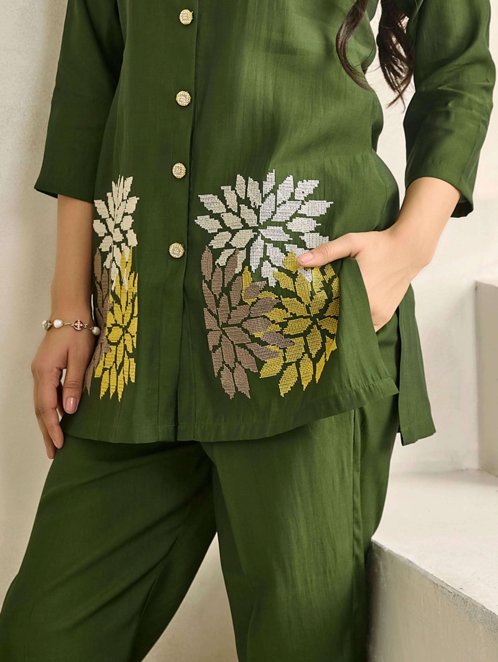 Green outfit with floral embroidery on a neutral background