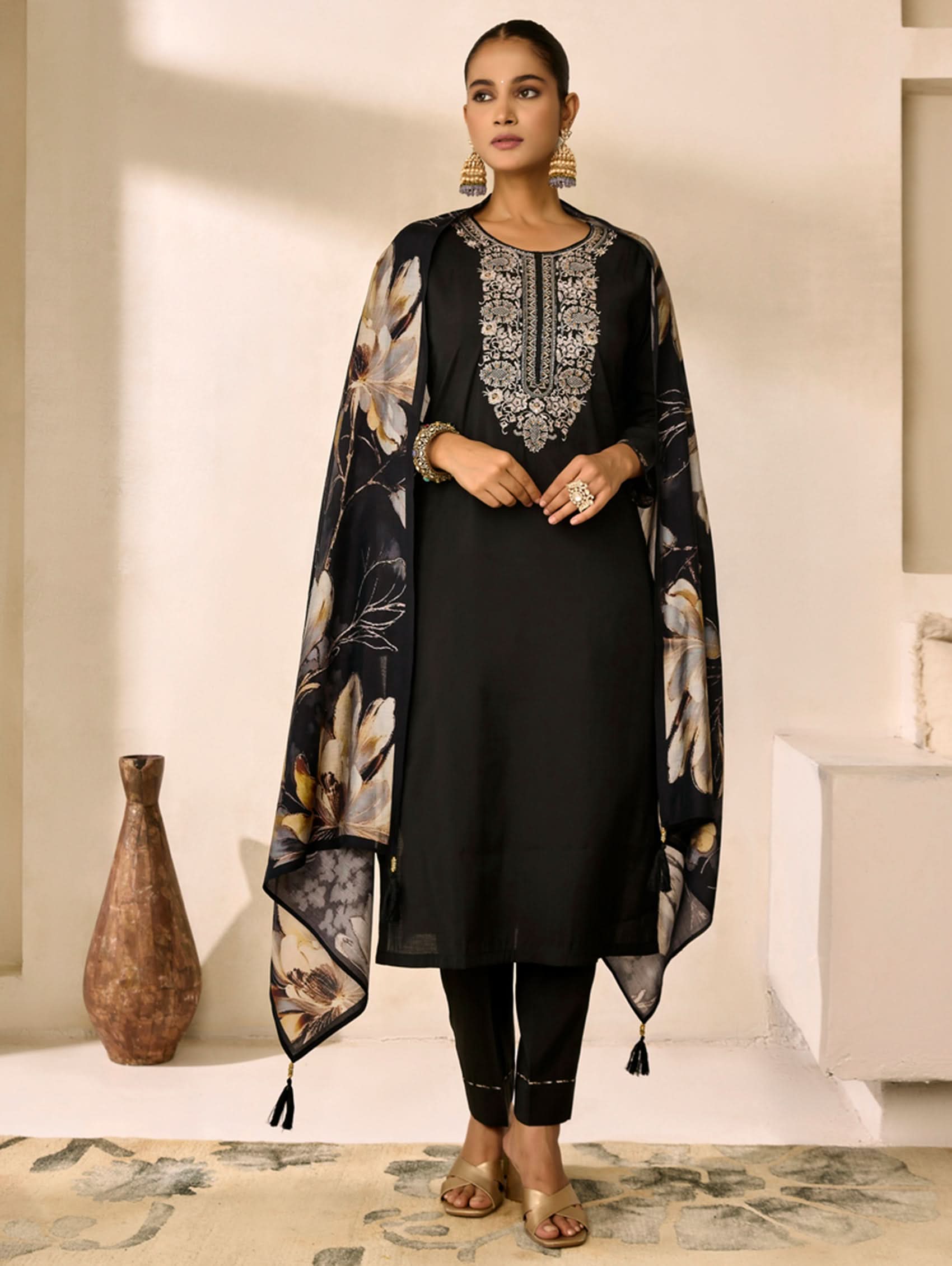 Woman wearing a black outfit with floral patterns in a minimalistic setting