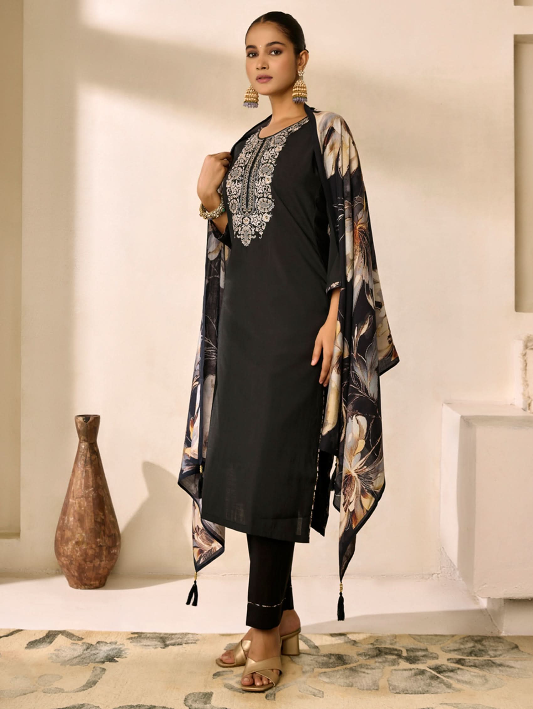 Woman wearing a black outfit with a floral kimono-style jacket in an indoor setting.