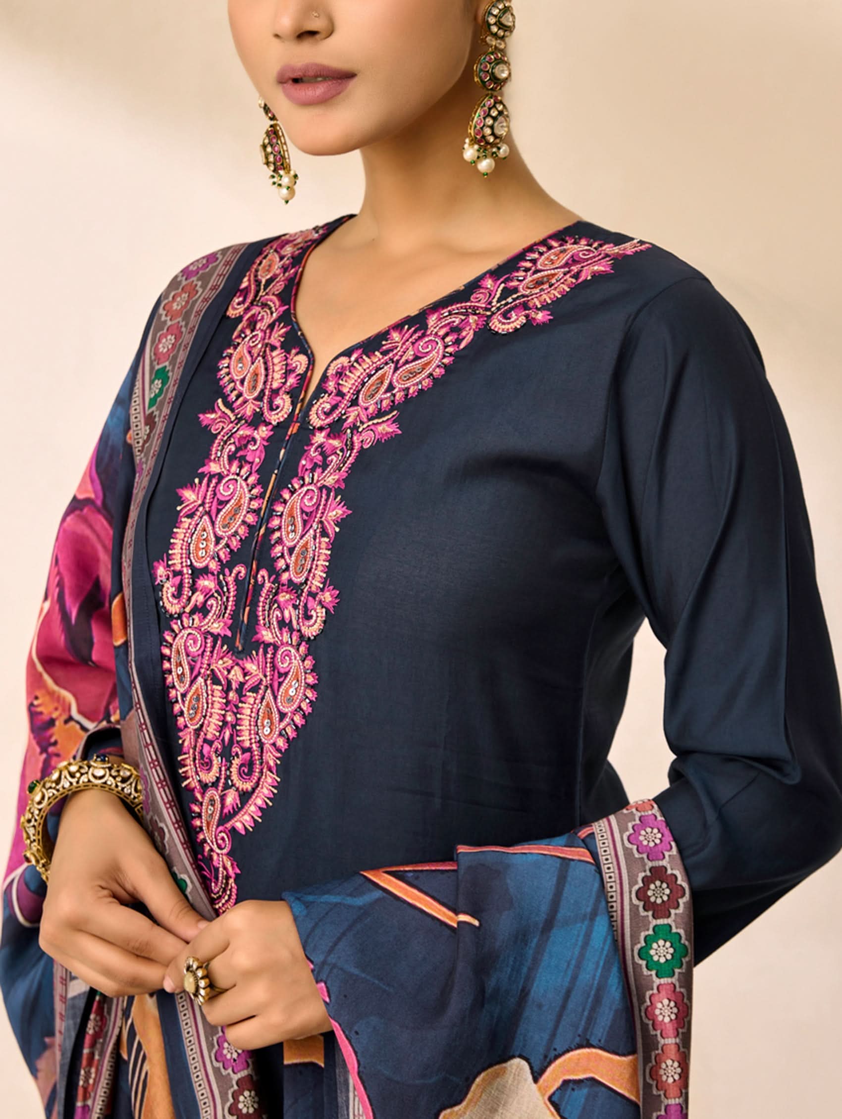 Navy blue traditional outfit with pink and orange embroidery on a beige background