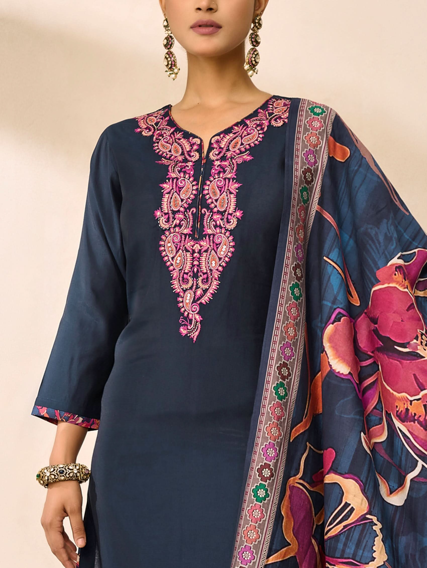 Navy blue embroidered dress with a colorful floral pattern on a beige background