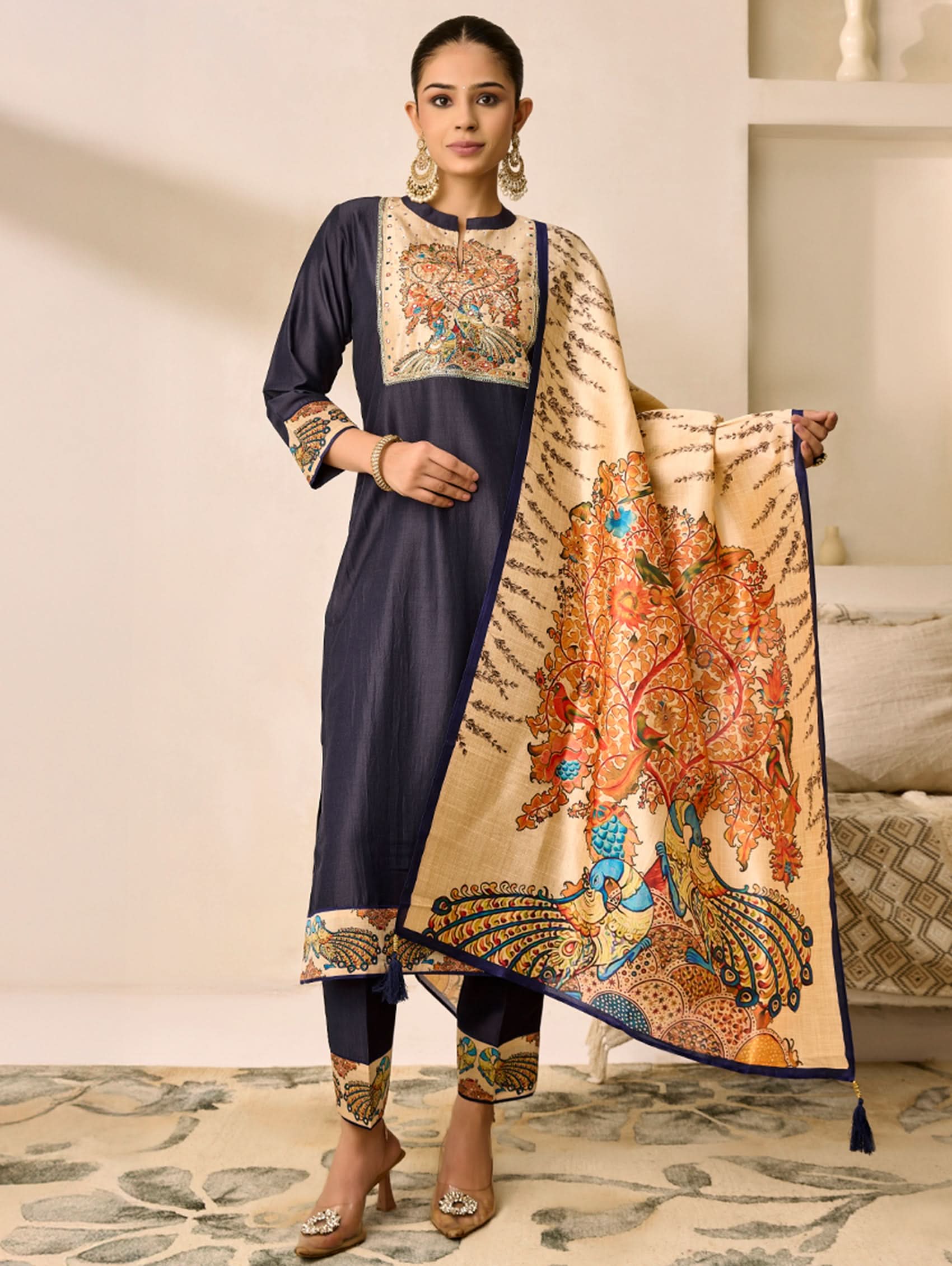 Woman wearing a navy blue and beige traditional outfit with a matching dupatta in a room.