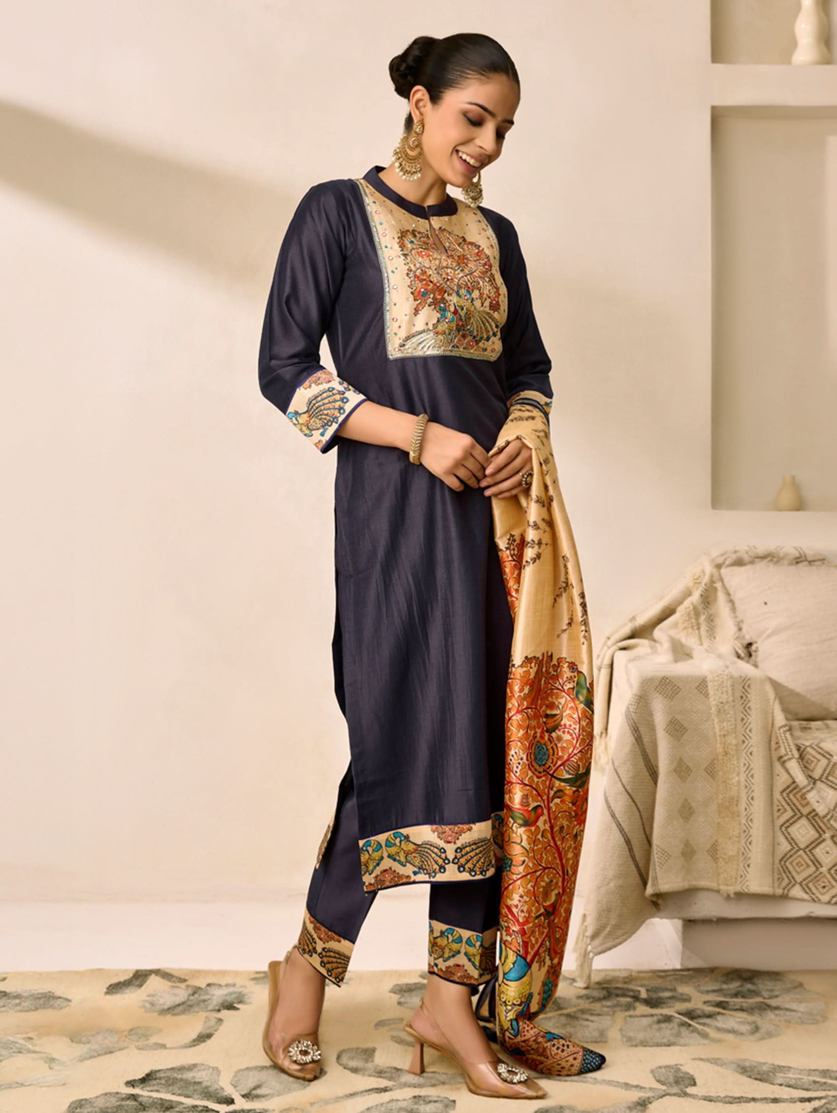 Woman wearing a navy blue traditional outfit with patterned dupatta in a room.