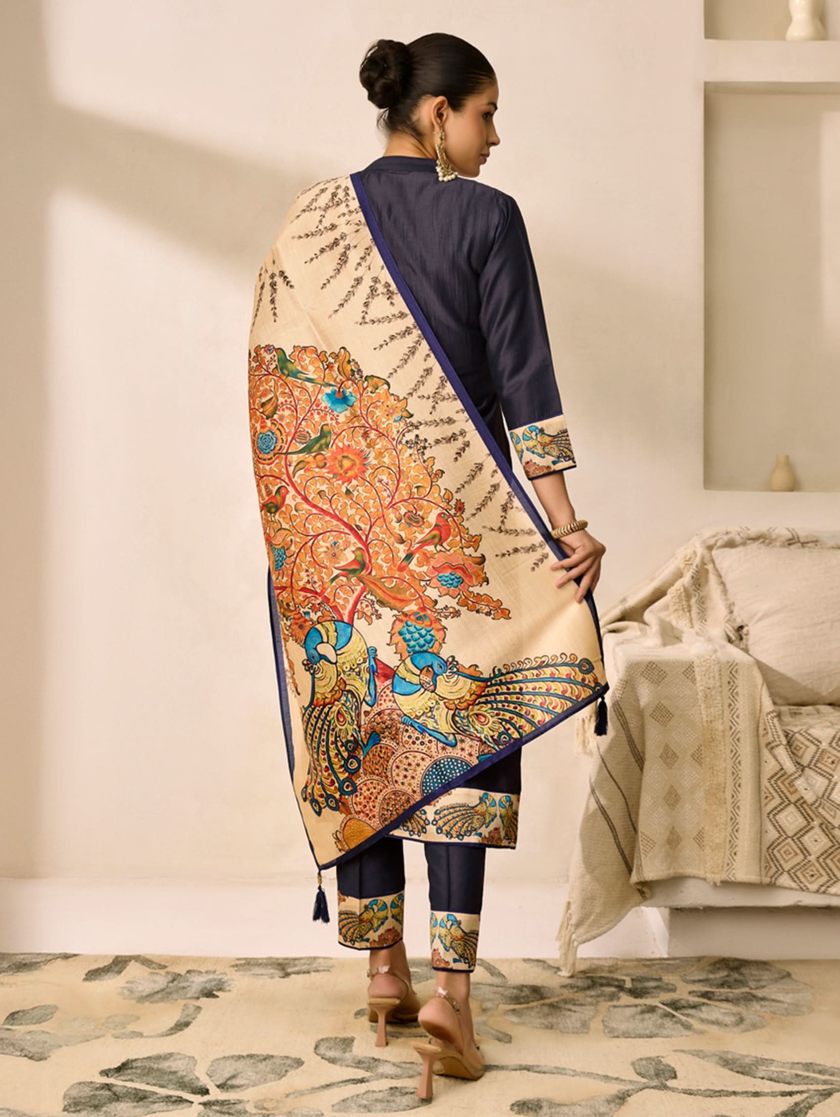 Woman wearing a traditional outfit with a colorful patterned dupatta in a room.