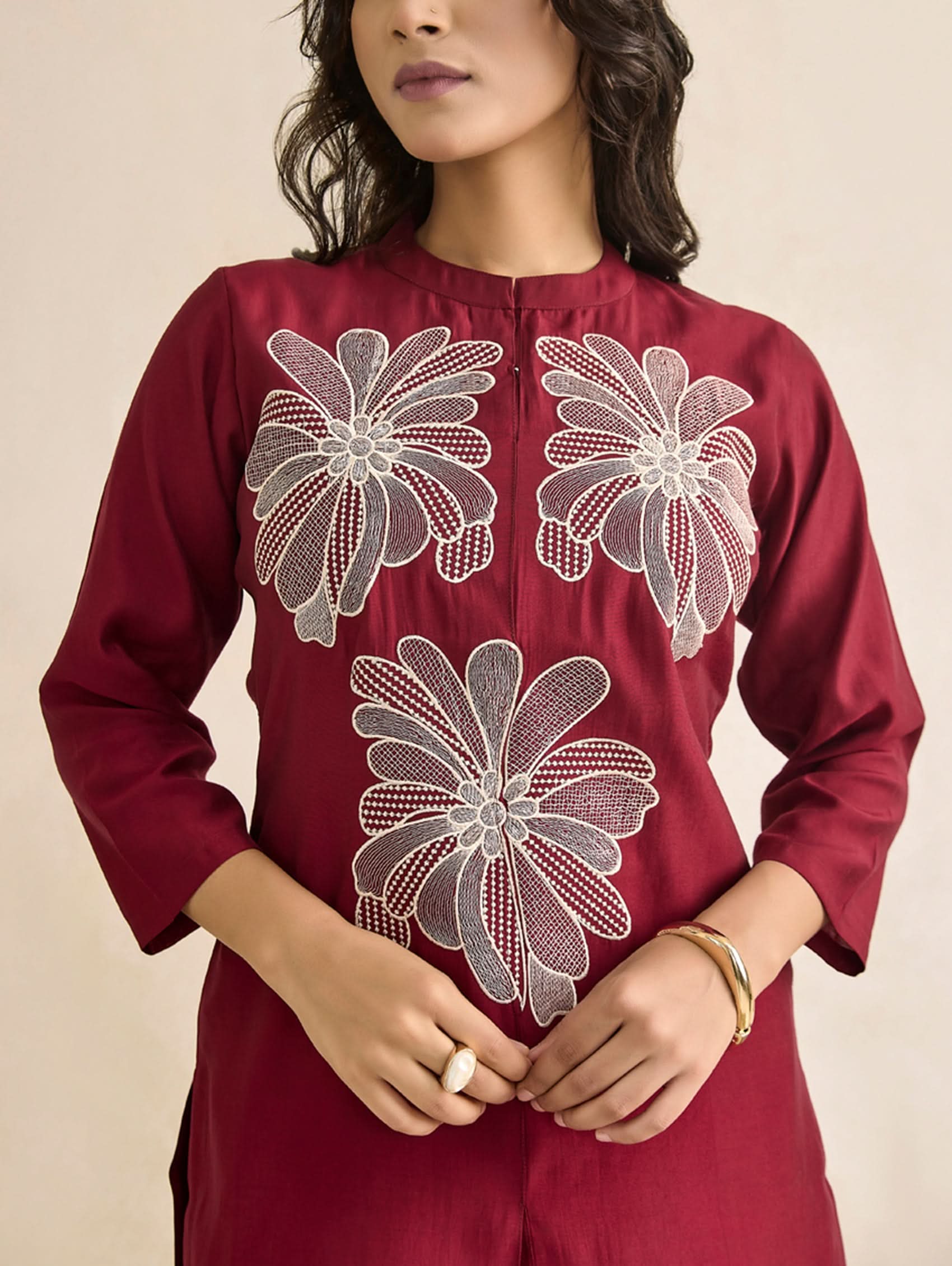 Maroon kurta with white floral embroidery on a beige background