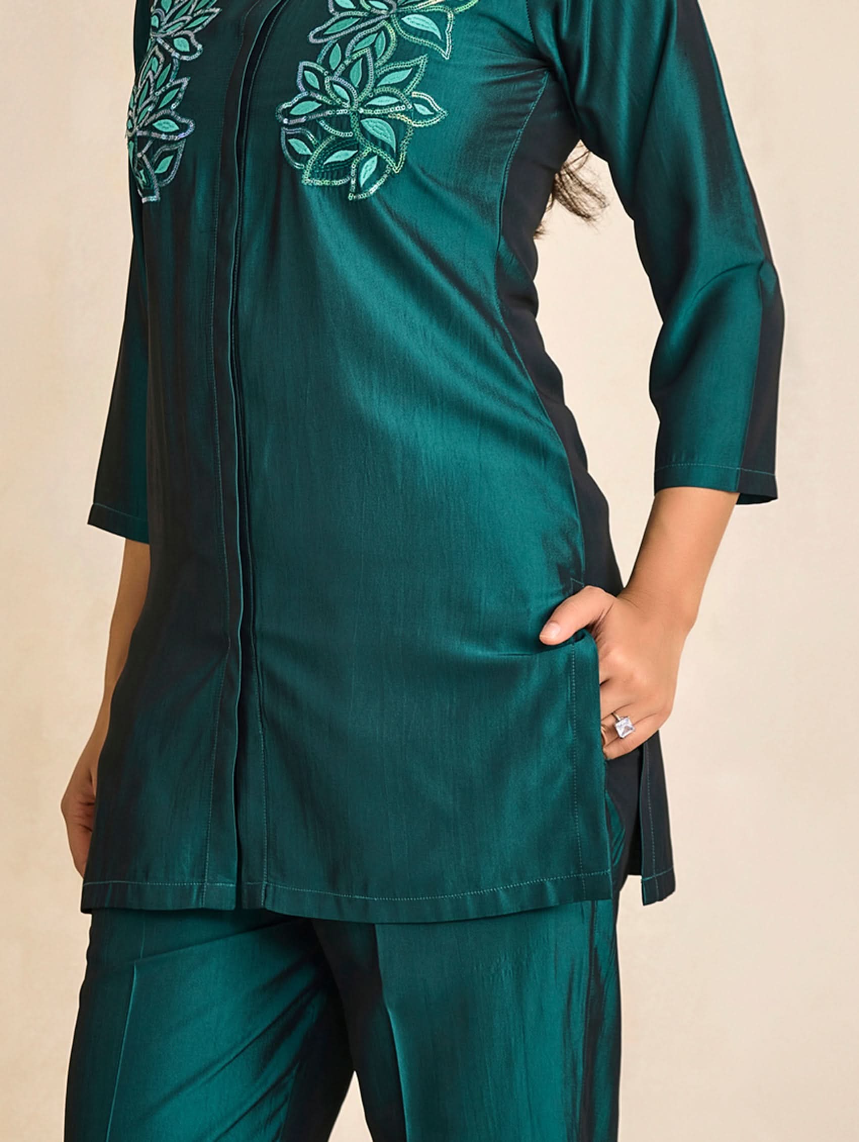 Teal outfit with leaf patterns on a beige background