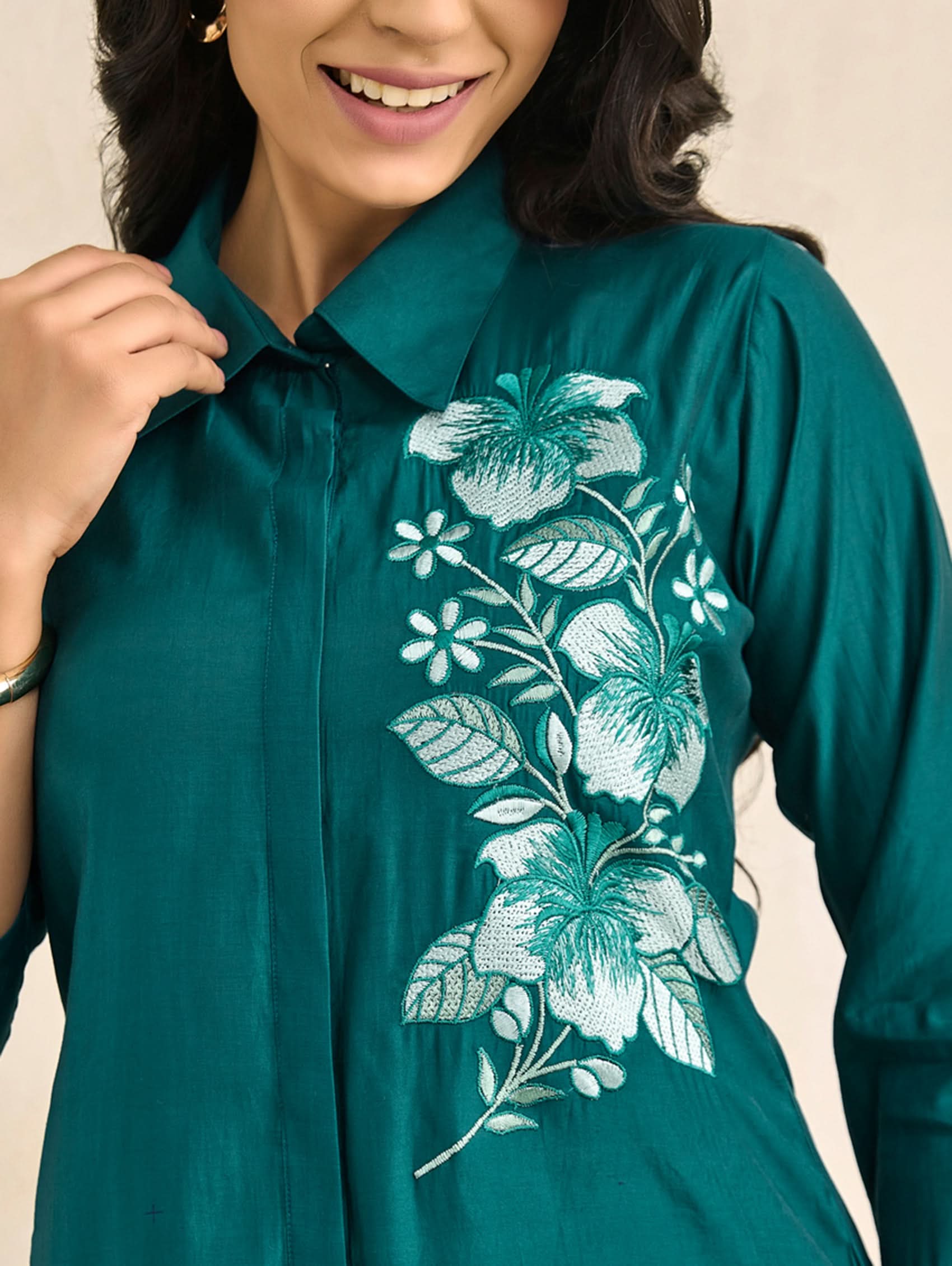Teal shirt with floral embroidery worn by a person