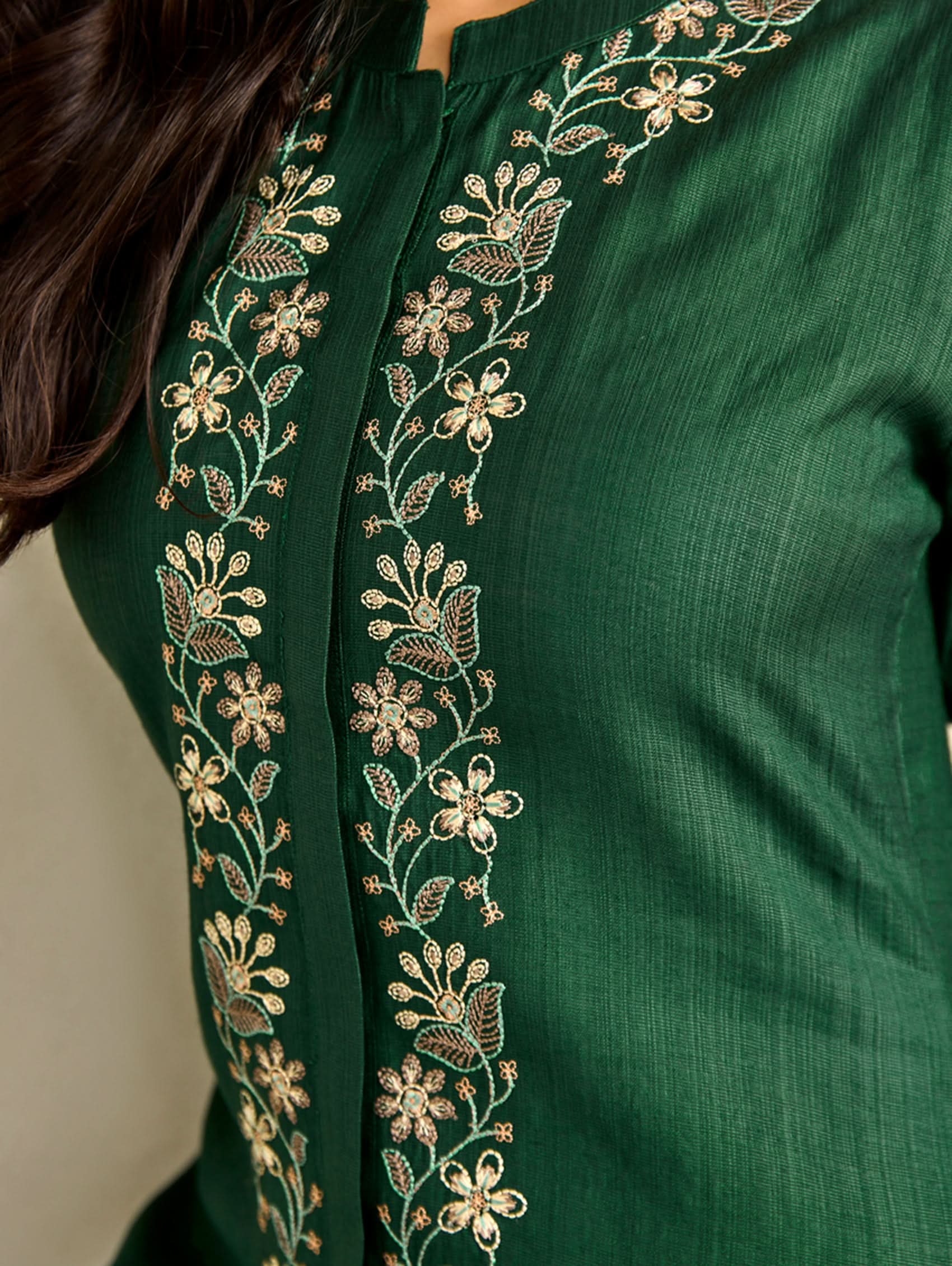 Green garment with gold embroidery on a plain background