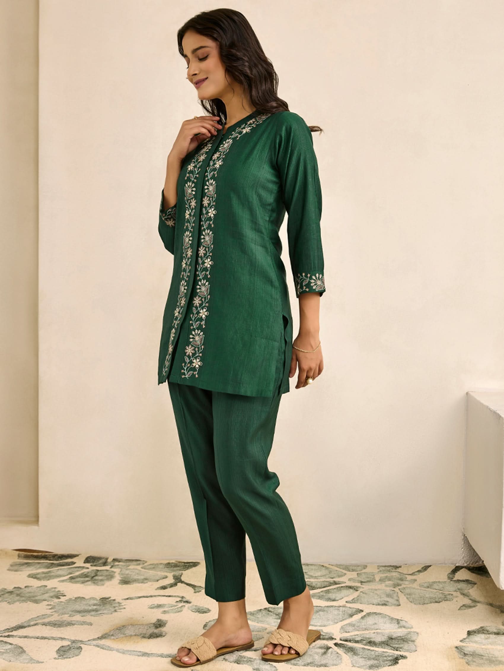 Woman wearing a green embroidered outfit on a neutral background
