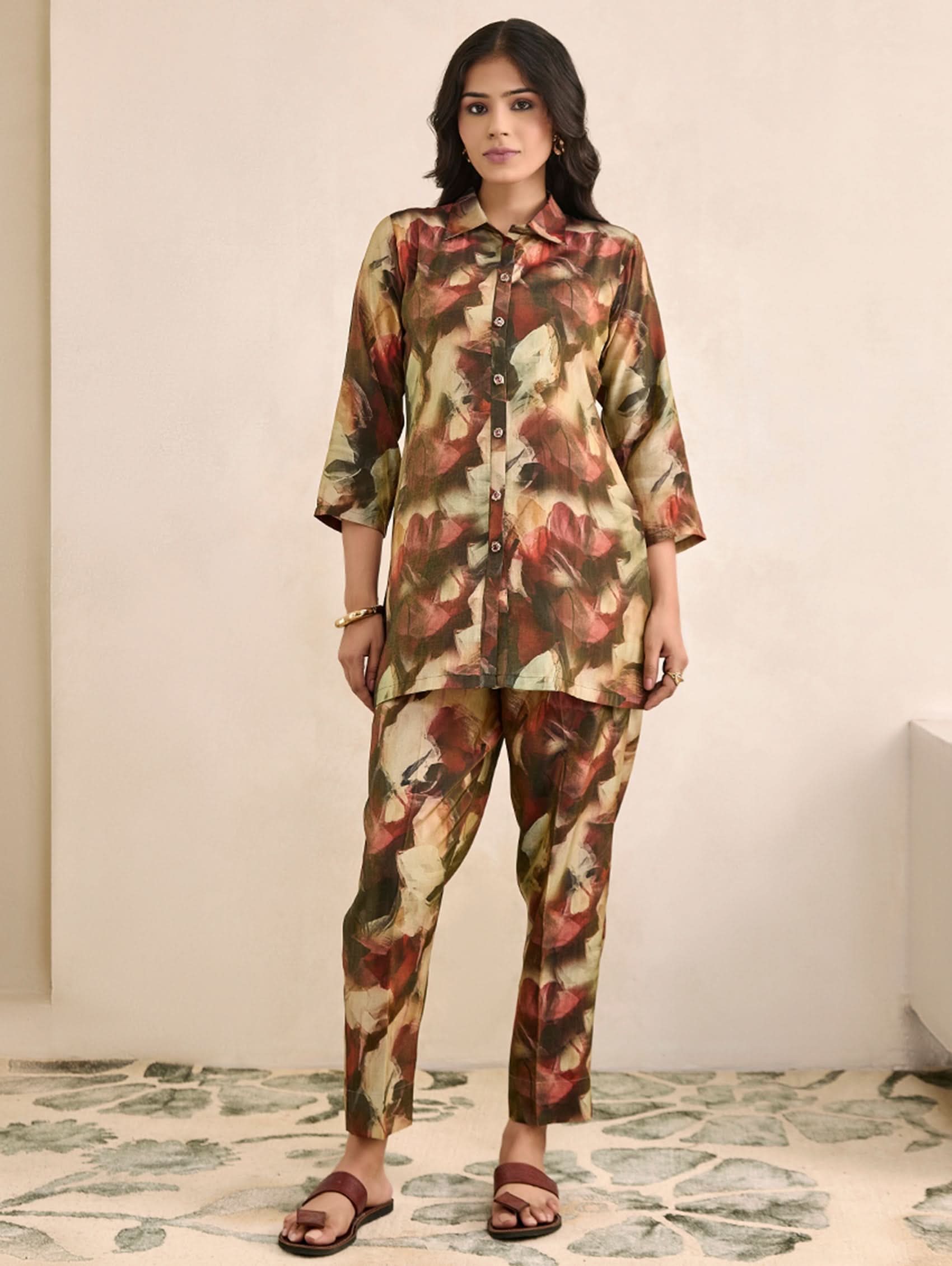 Woman wearing a floral outfit standing on a patterned rug.